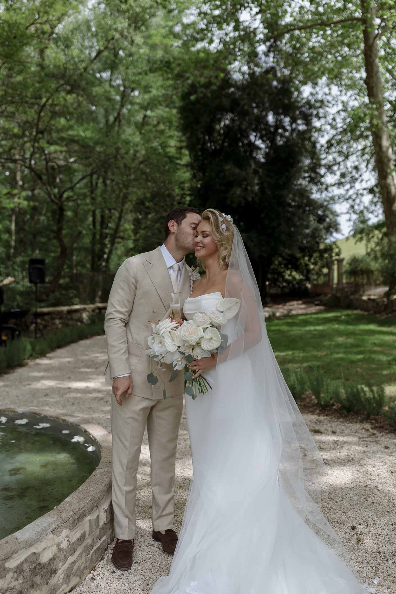 Bride and groom walking together on tree-lined pathway at garden estate venue