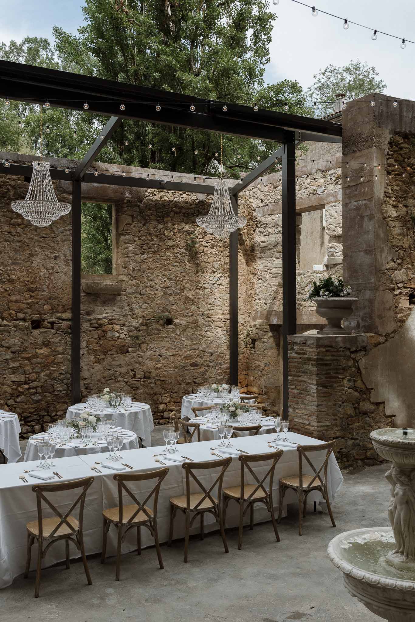 Reception dining setup in historic stone courtyard with string lights and white table linens