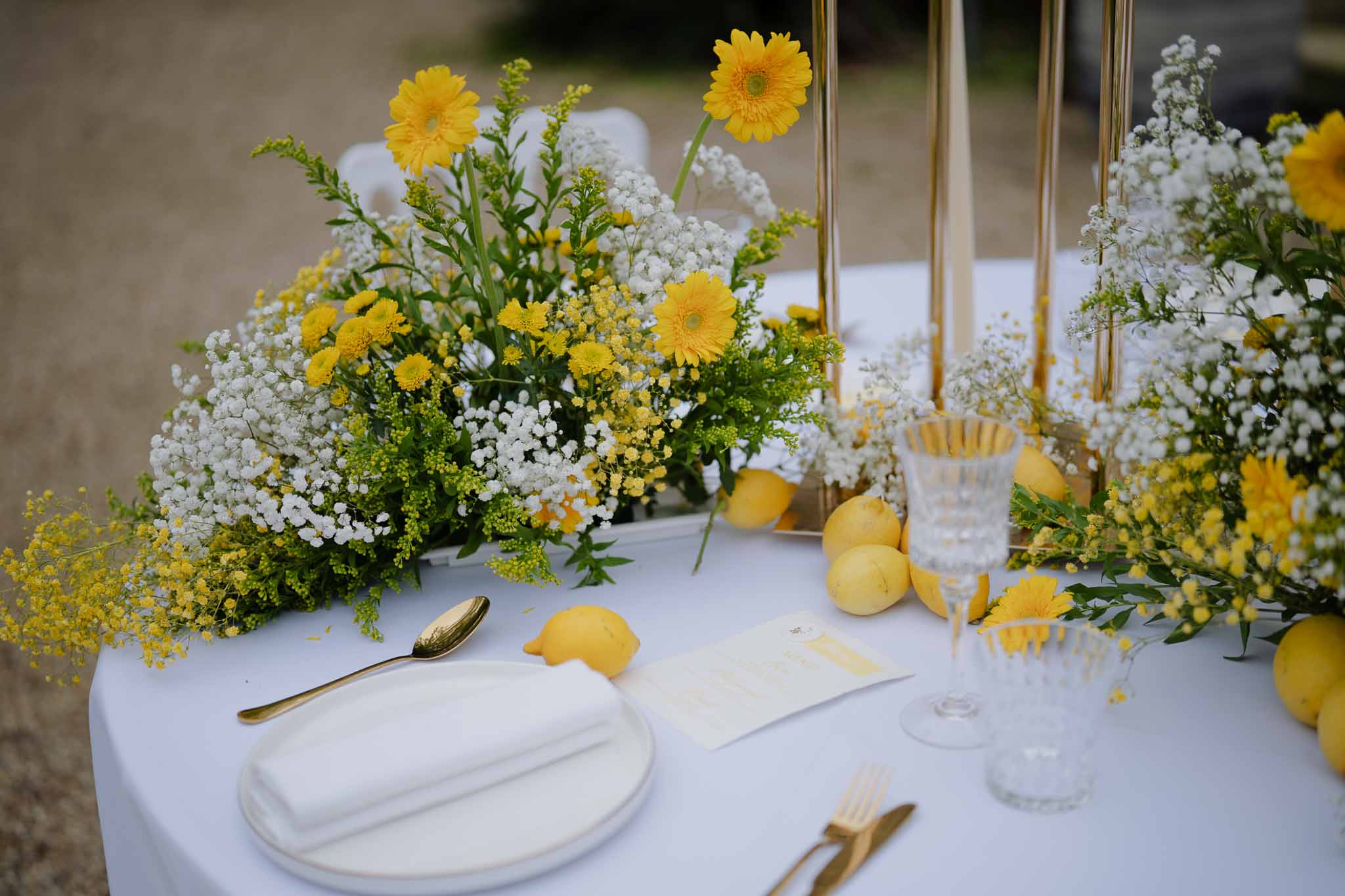 Yellow and white reception table setting with citrus-themed centerpieces and gold accents