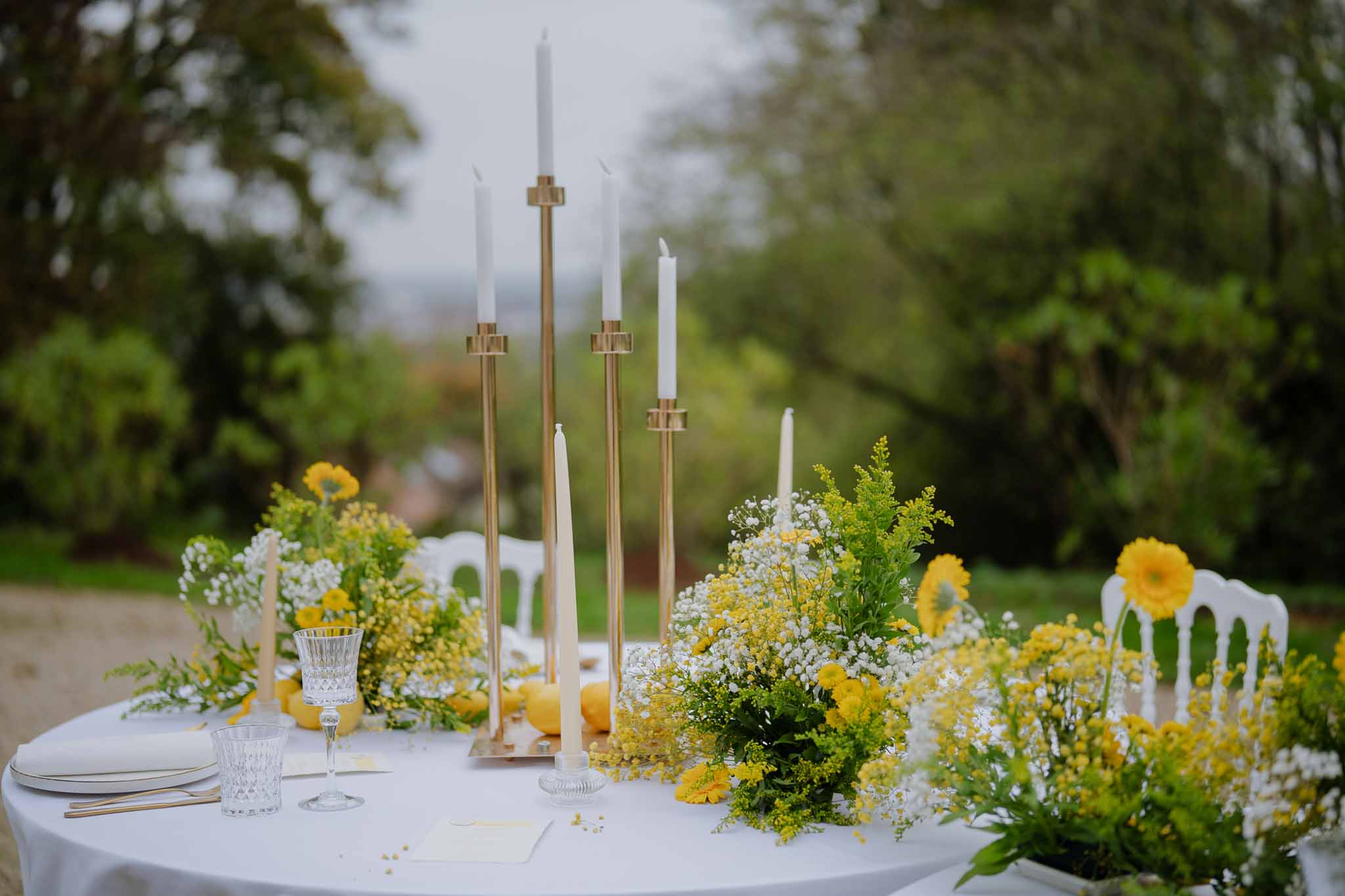 Wedding reception table setting with brass candelabra and floral centerpieces at outdoor garden venue