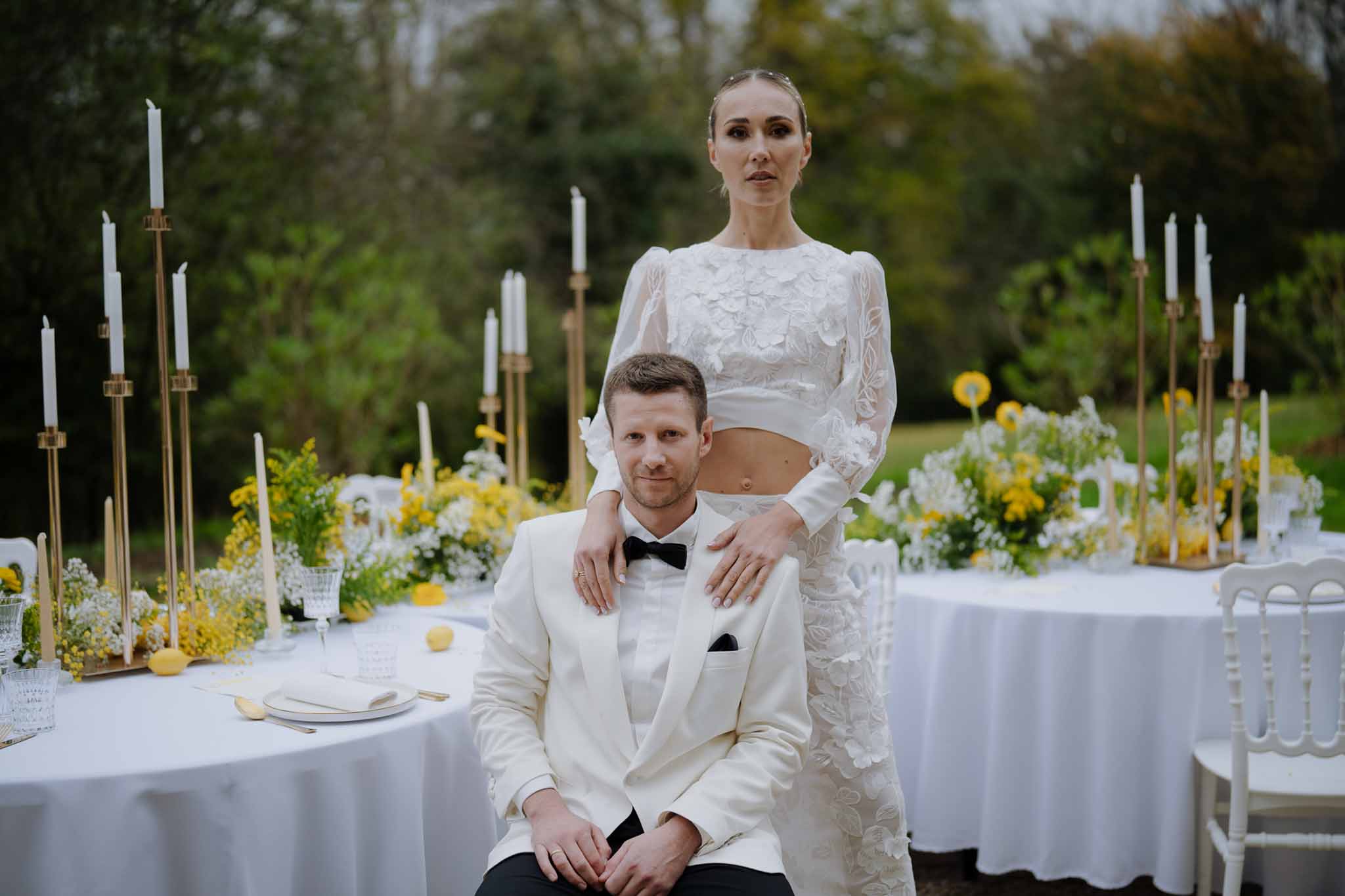 Bride and groom portrait at outdoor garden reception with white linens and gold candlelit tables