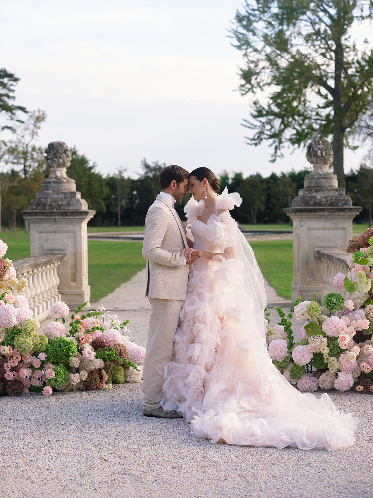 Bride and groom portrait in formal garden with stone balustrades and floral arrangements
