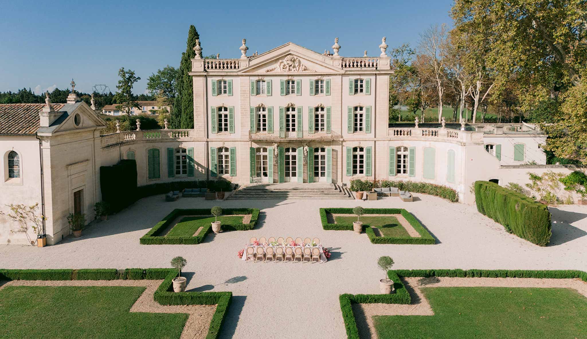 Aerial view of ceremony setup in formal château courtyard with geometric gardens