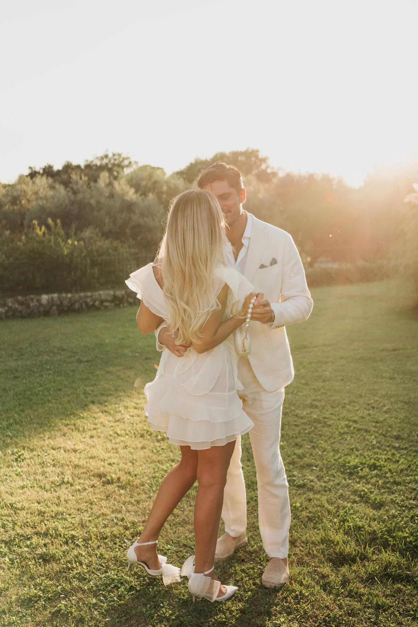 Couple embracing in meadow during golden hour at outdoor wedding venue
