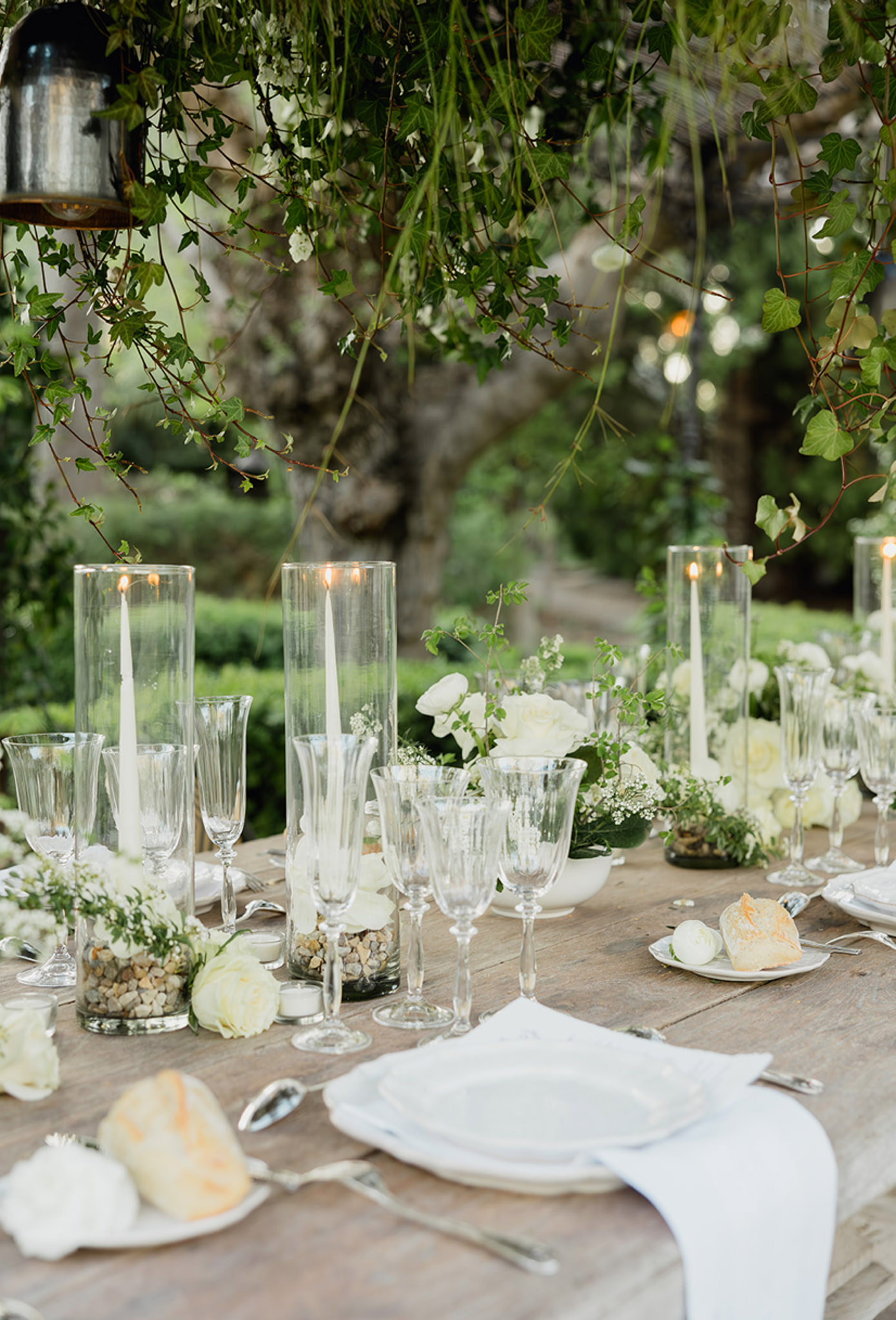 Wedding reception table setting with white linens and floral arrangements in outdoor garden venue