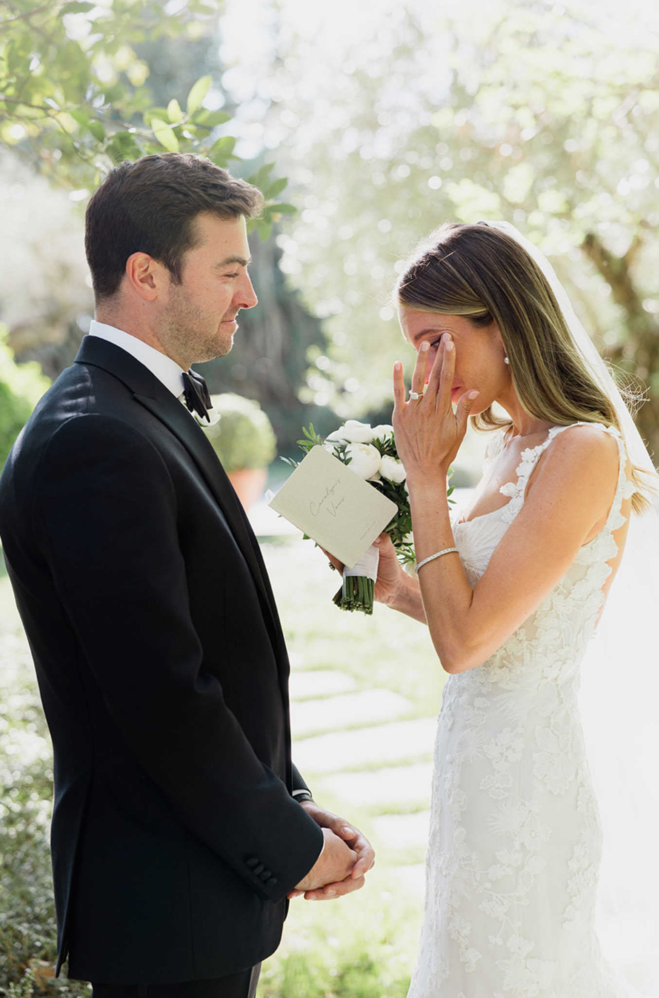 Bride and groom sharing intimate moment during garden ceremony with white blossoms backdrop