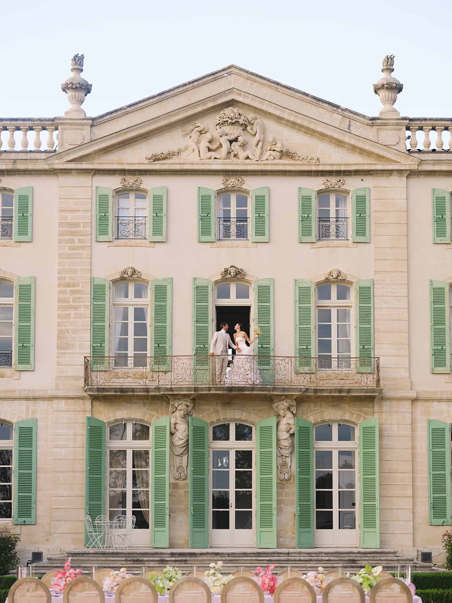 Bride and groom portrait on stone balcony of French mansion with classical architecture