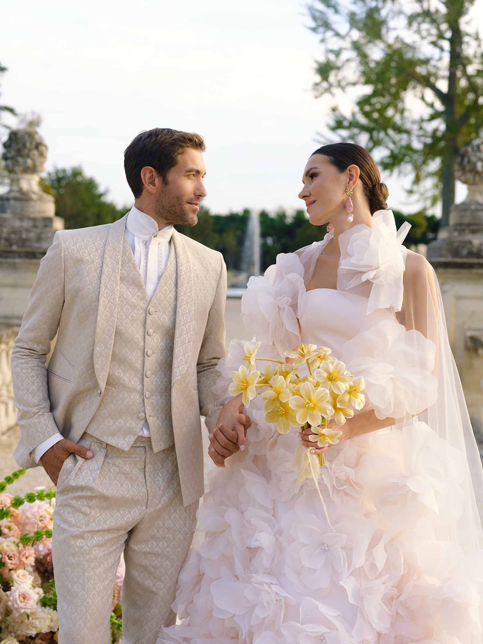 Bride and groom portrait on waterfront terrace with formal gardens and classical statuary