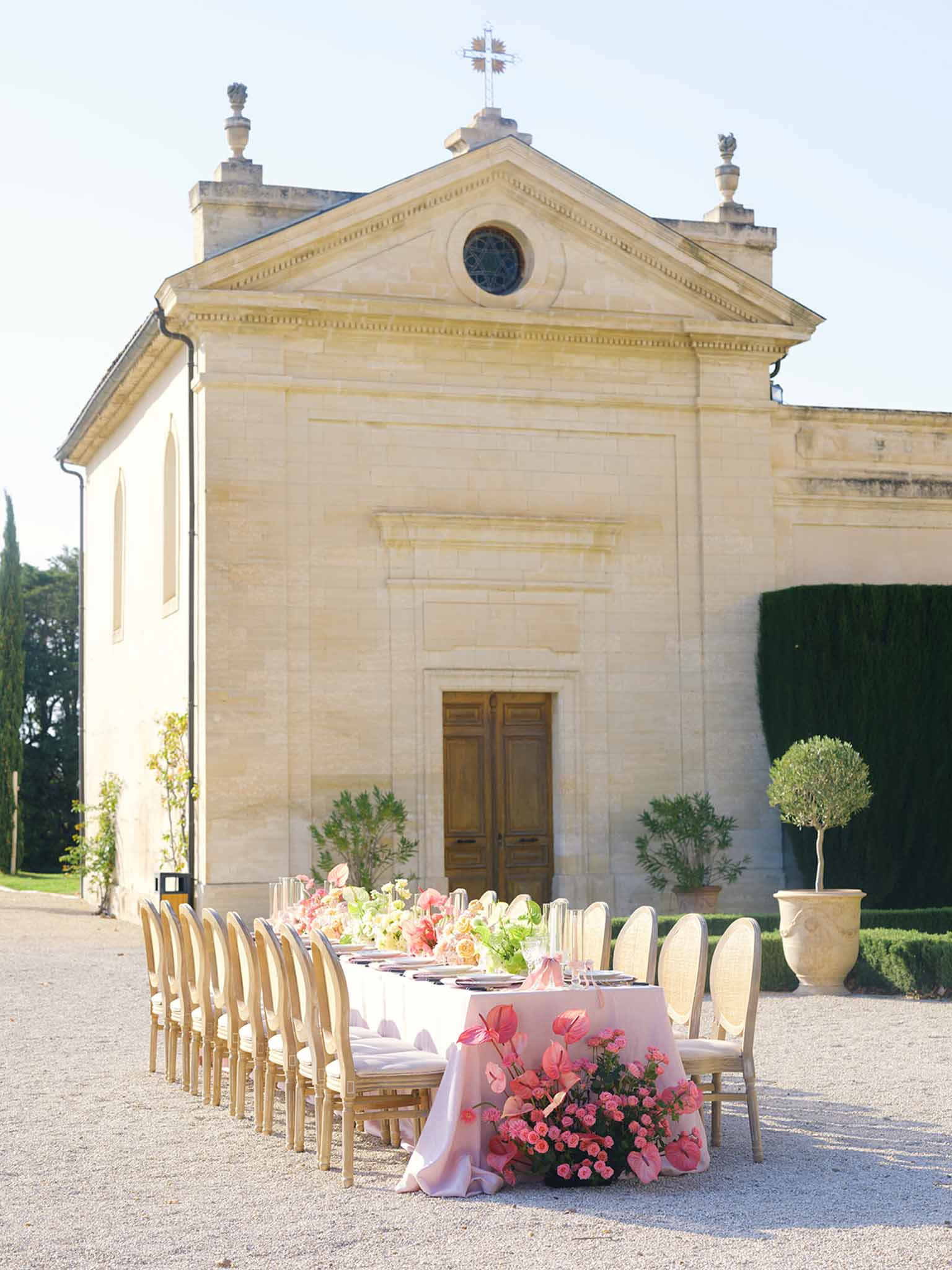 Stone chapel with outdoor reception table setup in formal courtyard garden