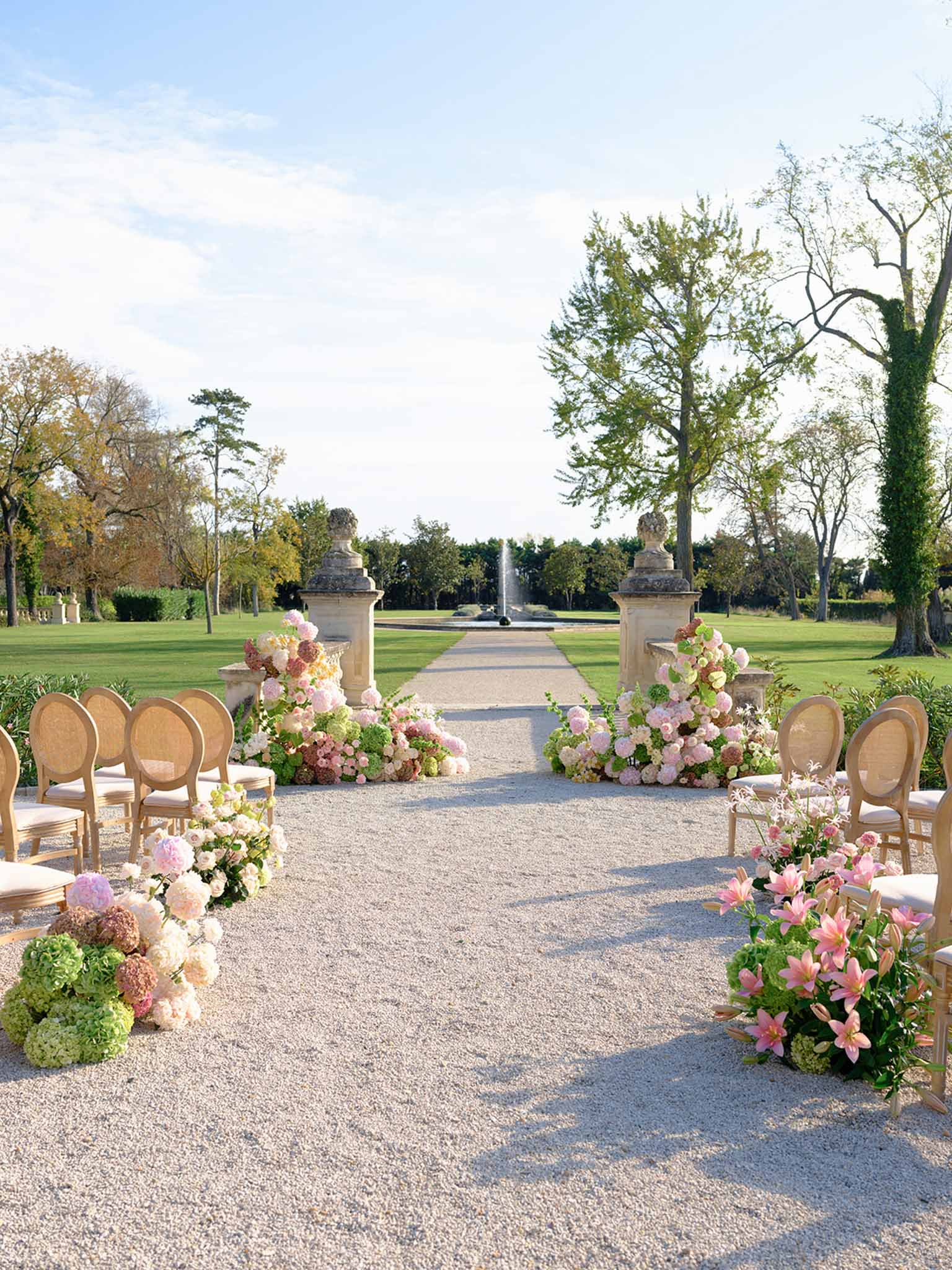 Formal garden ceremony setup with pink florals and fountain at estate venue