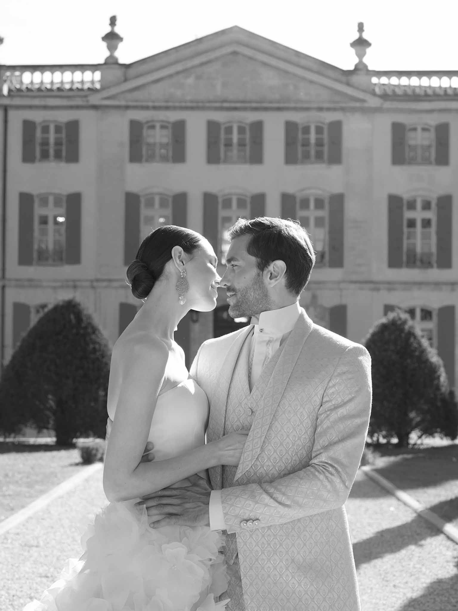 Bride and groom embracing in courtyard of neoclassical mansion estate