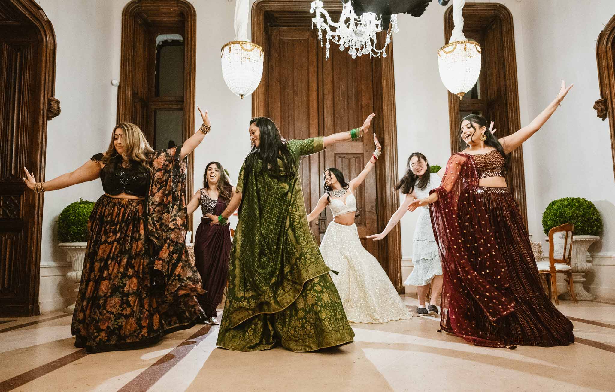 Group of women celebrating during wedding reception in classical ballroom with crystal chandeliers