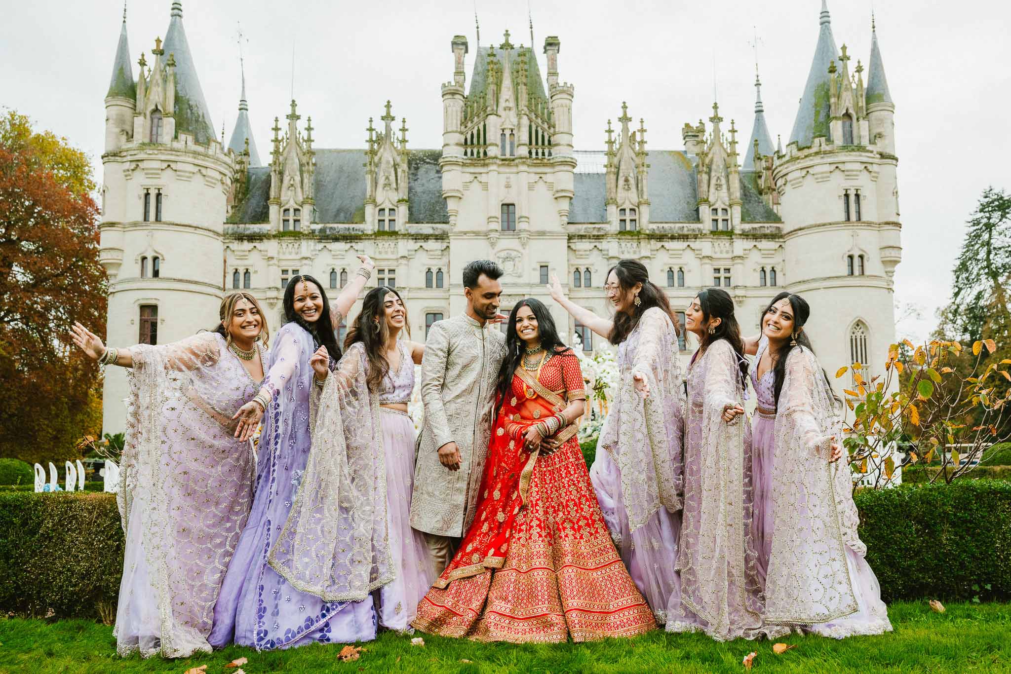 Bridal party in traditional Indian attire posing on castle grounds with Gothic architecture backdrop
