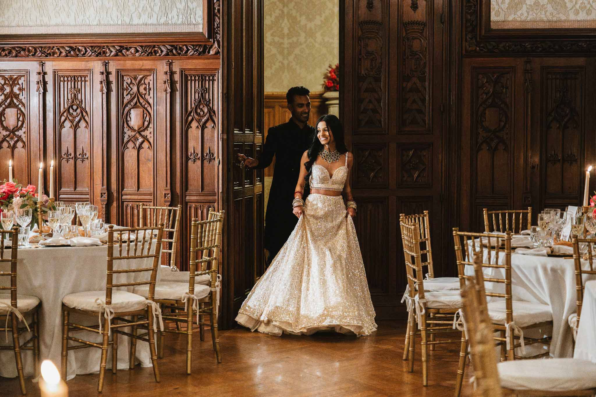 Bride and groom grand entrance in ornate ballroom with gold chiavari chairs and candles