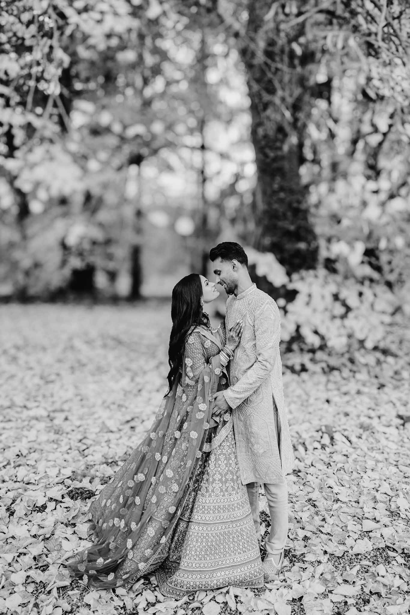 Bride and groom in traditional Indian wedding attire sharing intimate moment in flowering garden