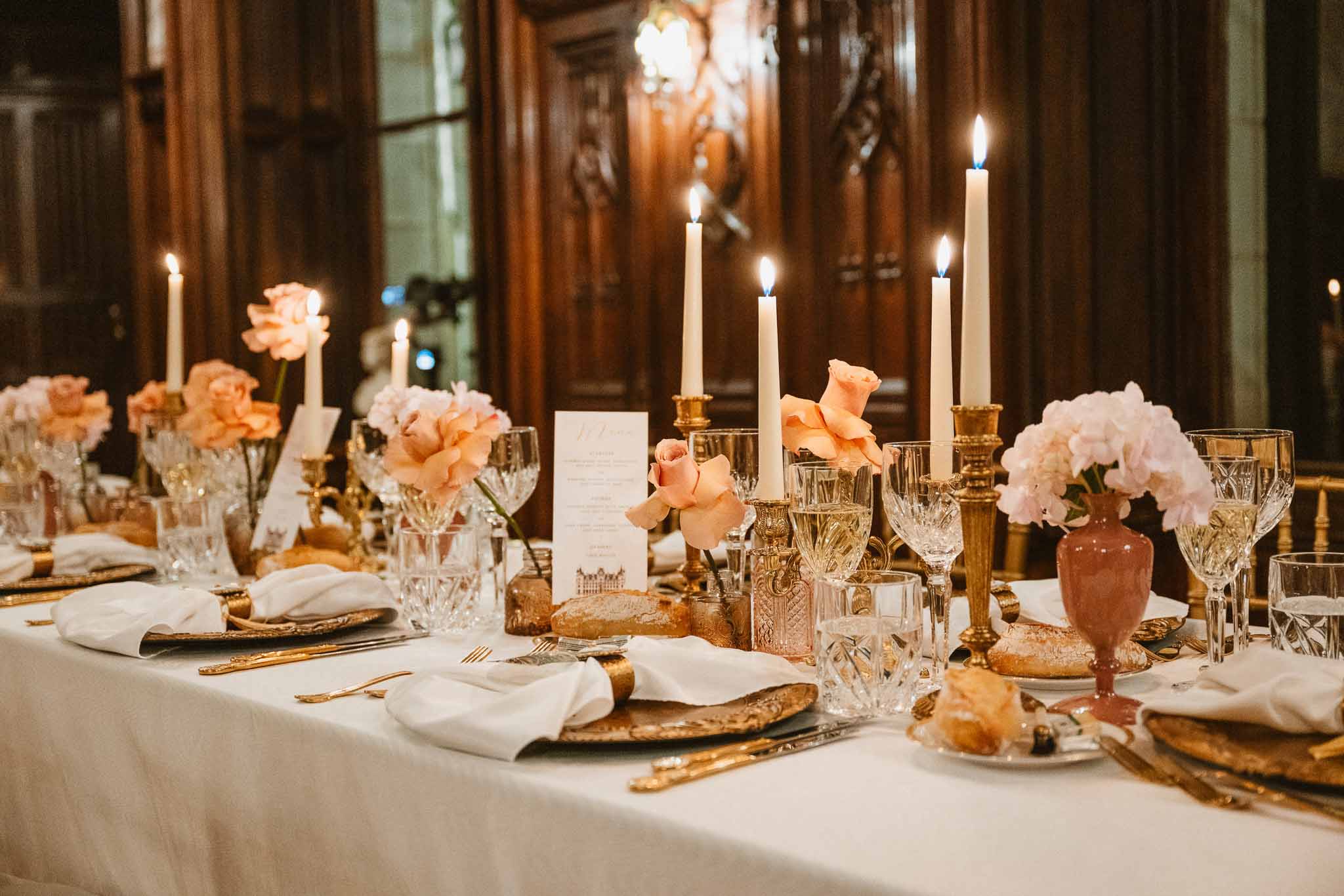 Elegant reception table setting with gold chargers and floral centerpieces in formal indoor venue