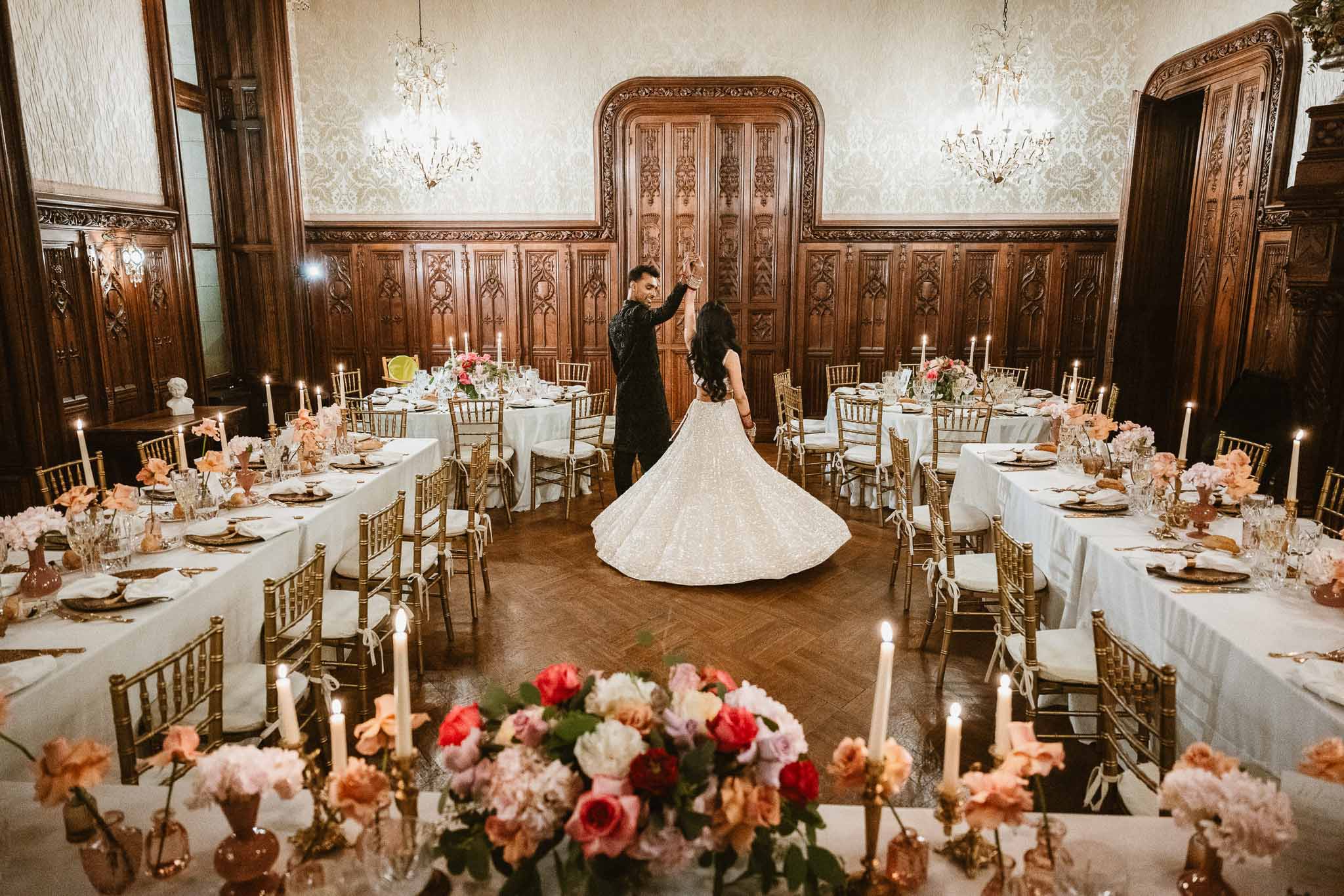 Bride walking through ornate ballroom reception with gold chairs and floral centerpieces