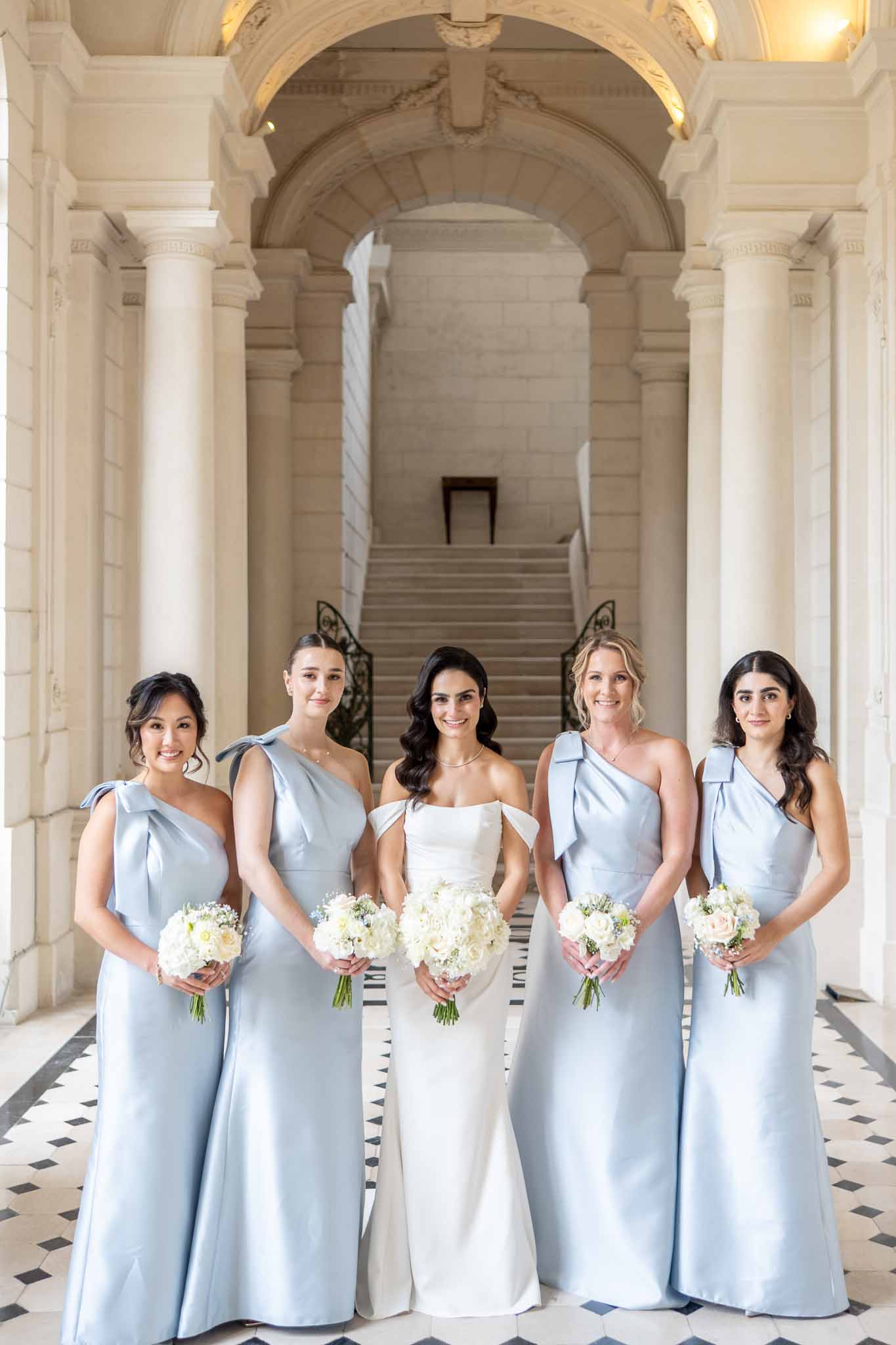 Bridal party portrait with bride and bridesmaids in classical architectural corridor with columns