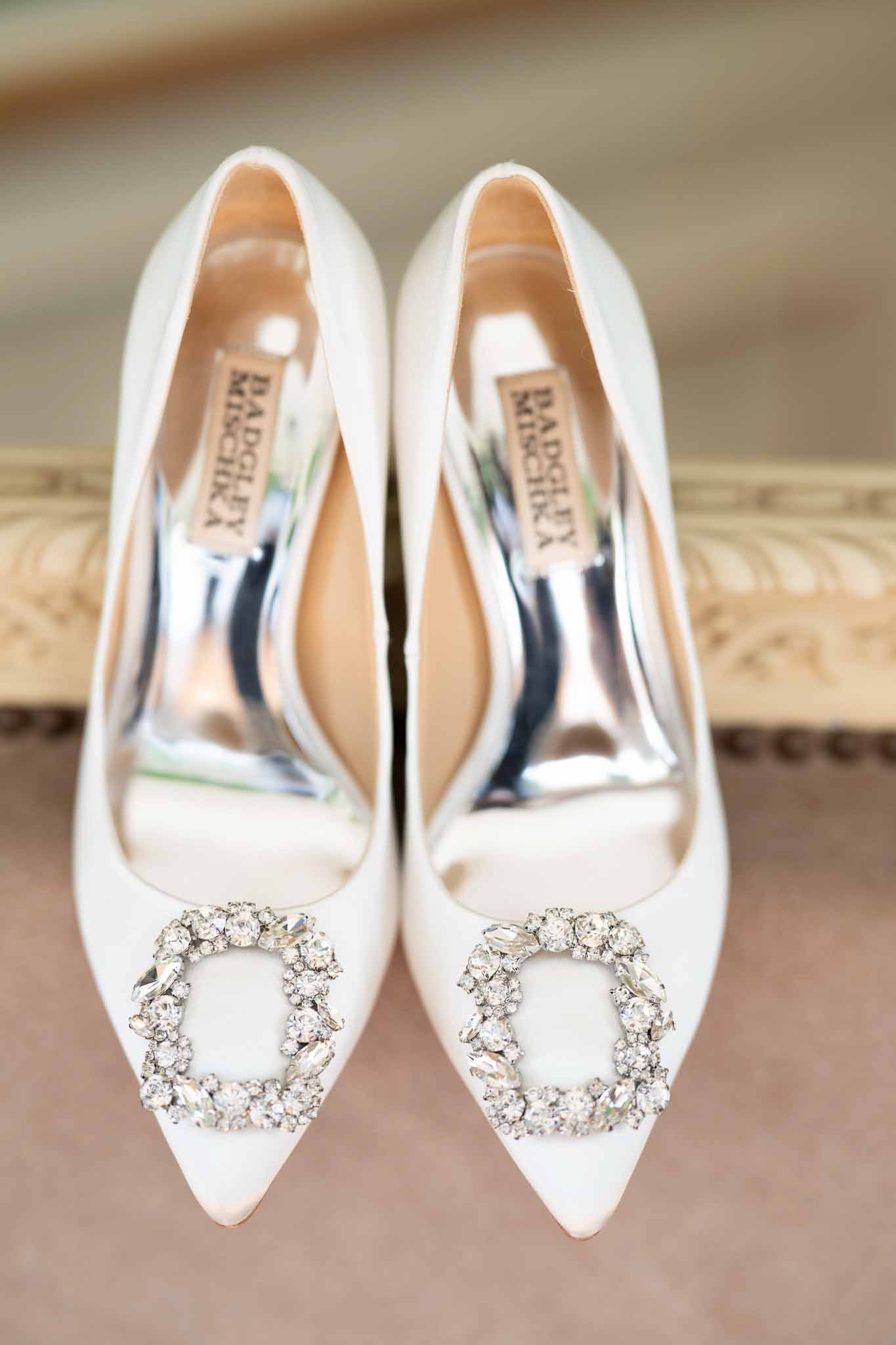 Ivory Badgley Mischka bridal shoes with crystal buckles on neutral fabric surface