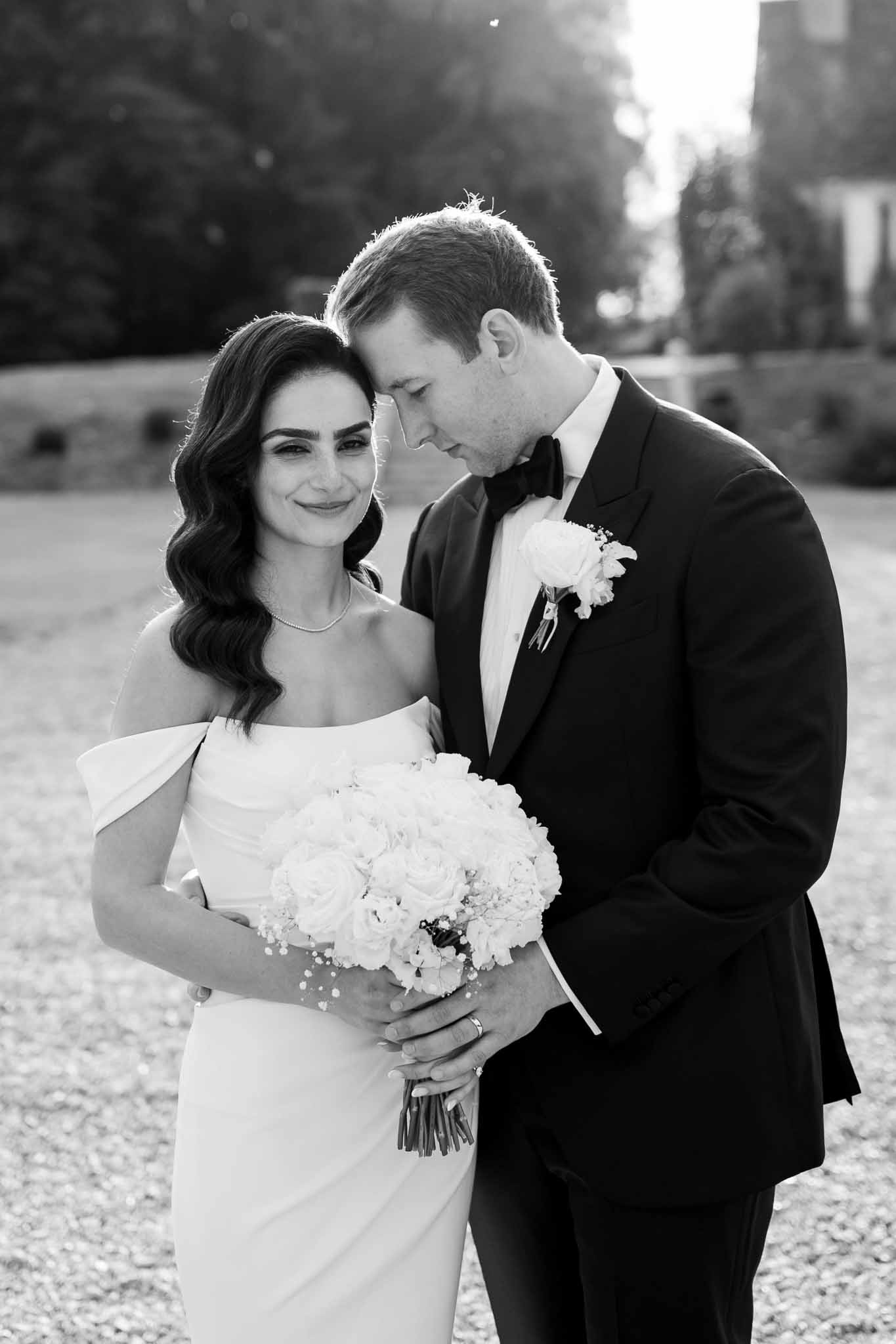 Black and white bride and groom portrait in courtyard with hedge backdrop