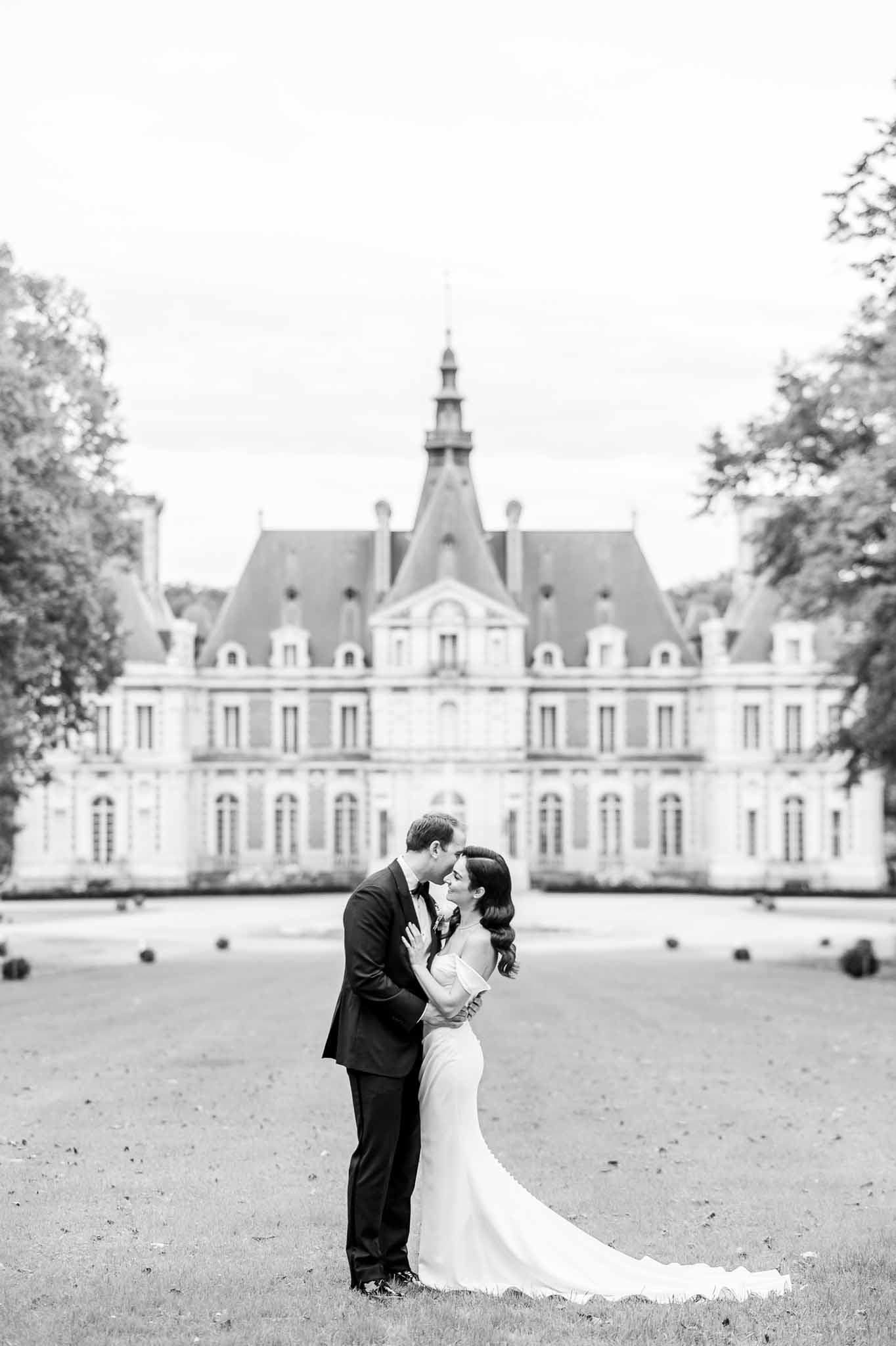 Bride and groom portrait in château courtyard with formal gardens and historic architecture