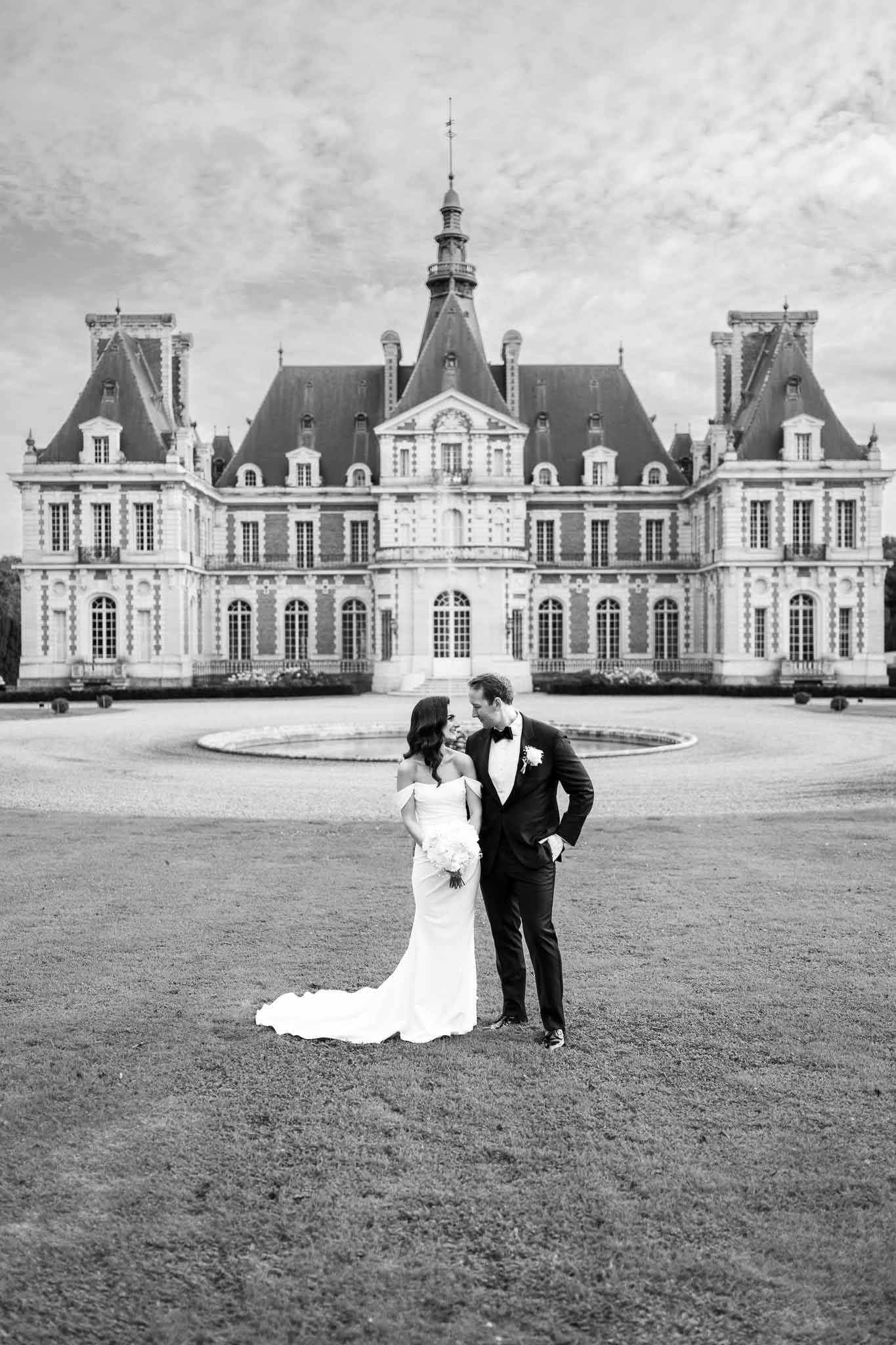 Bride and groom portrait in château courtyard with classical French architecture backdrop
