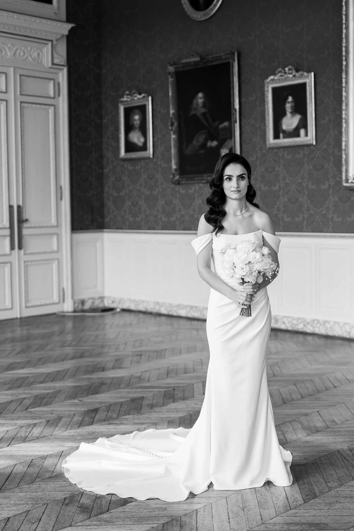 Bride in white gown holding bouquet in classical interior with herringbone floors and neoclassical architecture