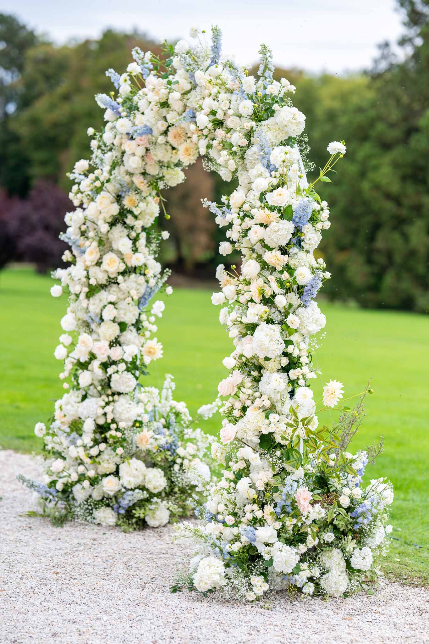 Floral ceremony arch with ivory roses and peach blooms in garden wedding setting