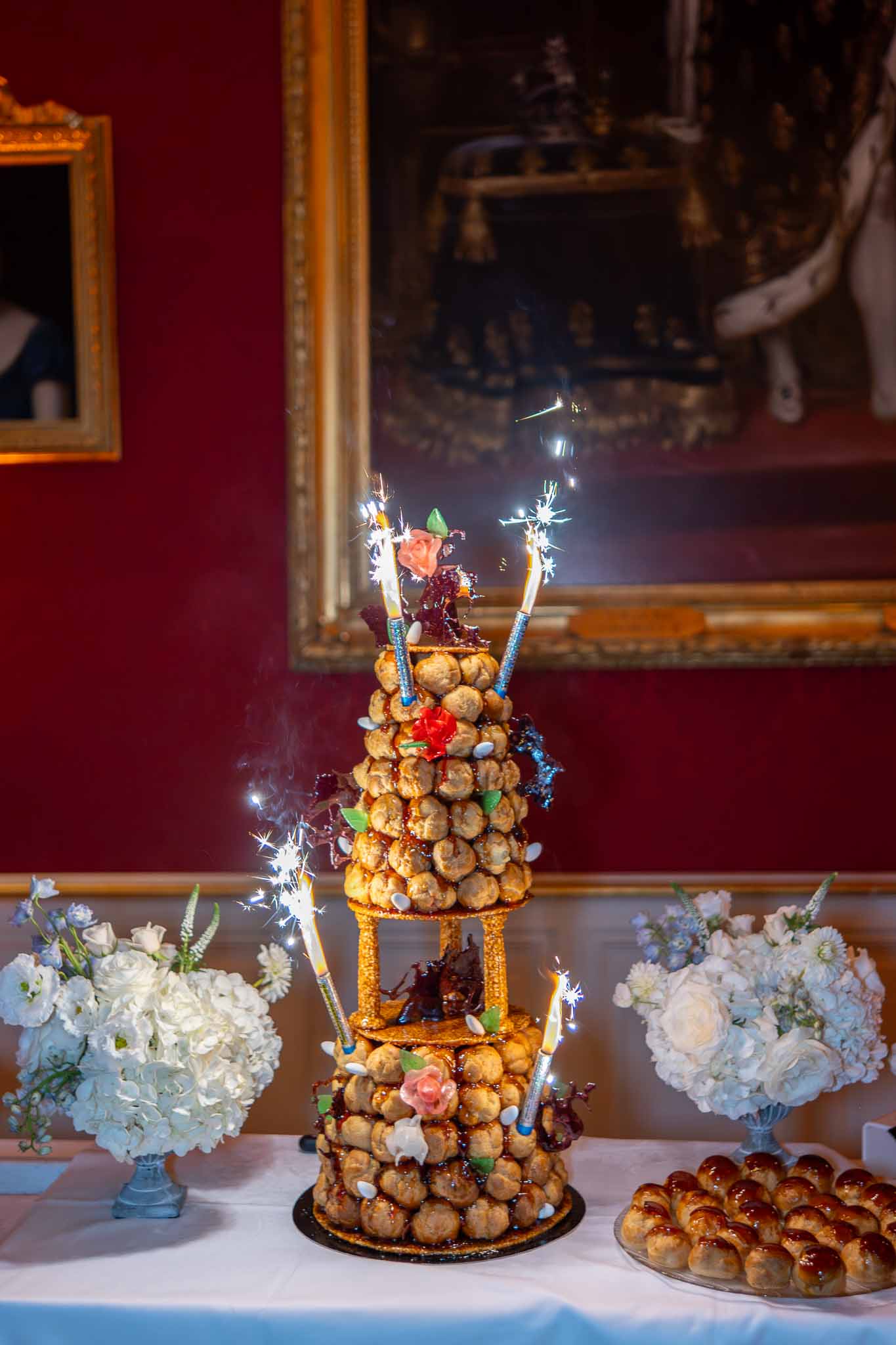 Traditional French croquembouche dessert display with coral roses and burgundy flowers at château reception