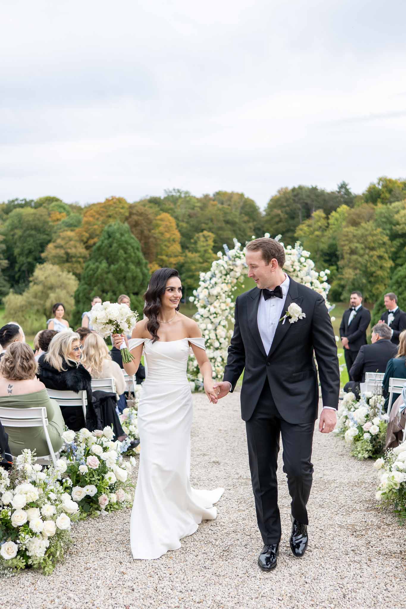 Bride and groom walking down aisle after outdoor garden ceremony with floral installations