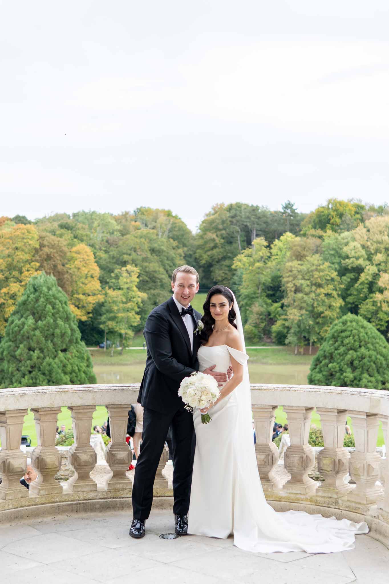 Bride and groom formal portrait on stone balcony overlooking manicured grounds