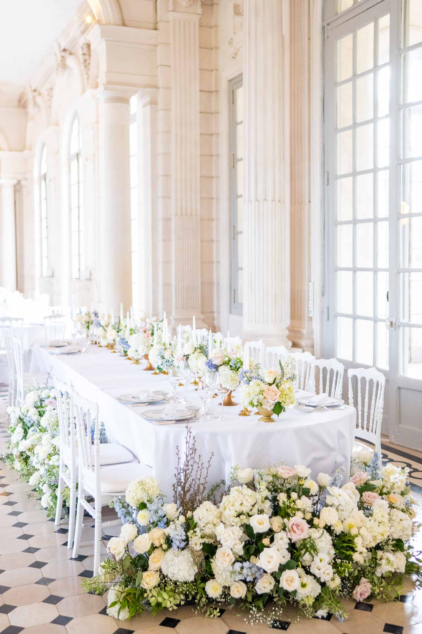 Reception dining setup with white linens and floral arrangements in neoclassical venue with columns