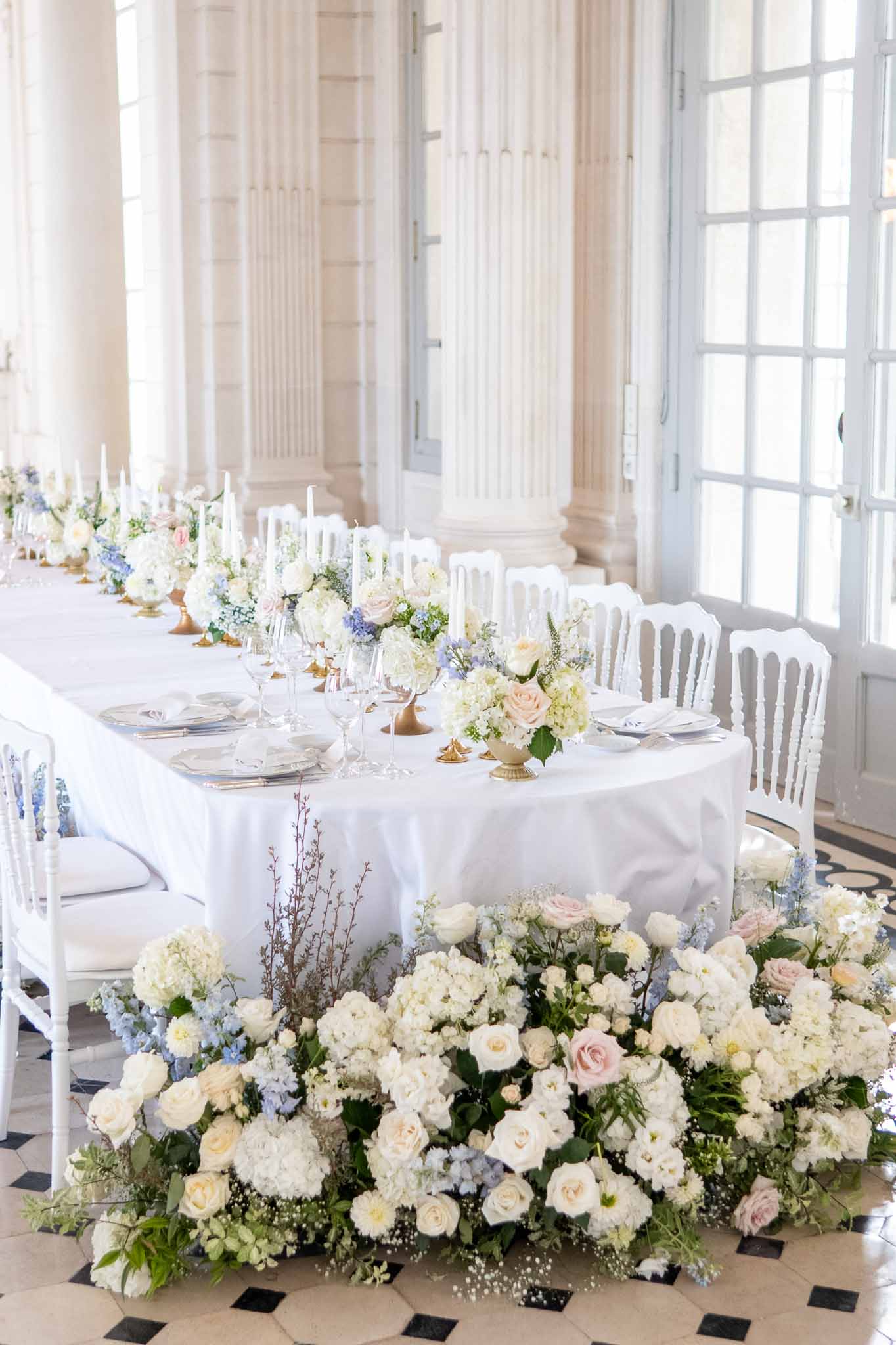 Elegant reception tablescape with floral runner in classical venue with columns and diamond floor