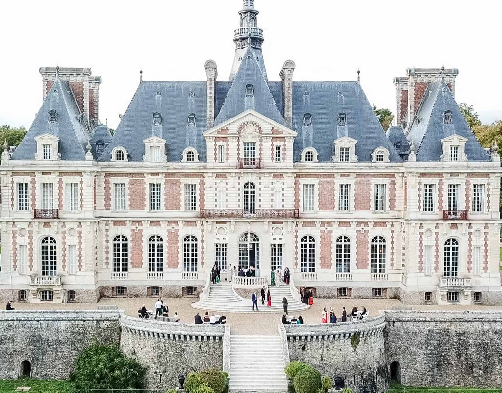 Grand French château with Renaissance architecture and wedding guests in formal courtyard setting