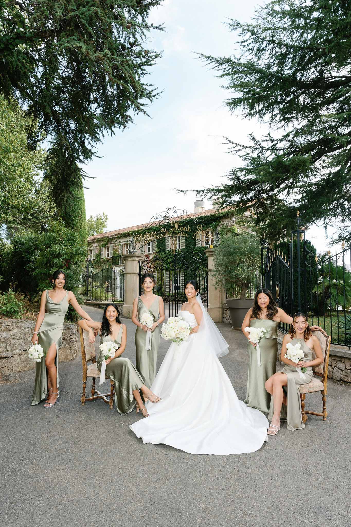 Bridal party portrait with bride in ivory gown and bridesmaids in sage dresses at stone estate courtyard