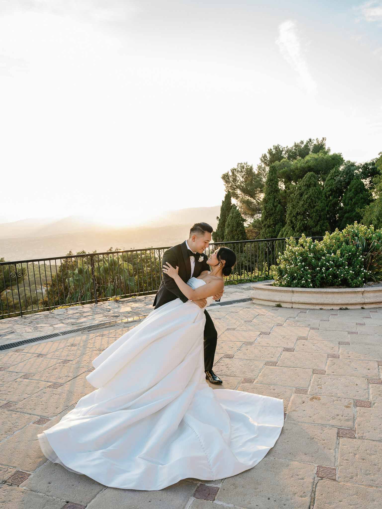 Bride and groom embracing on Mediterranean terrace with cypress trees and flowering vines