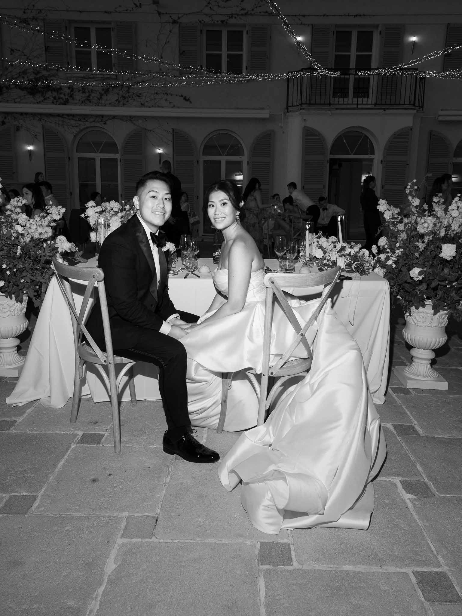 Bride and groom seated at reception table with classical architecture and candlelit decor