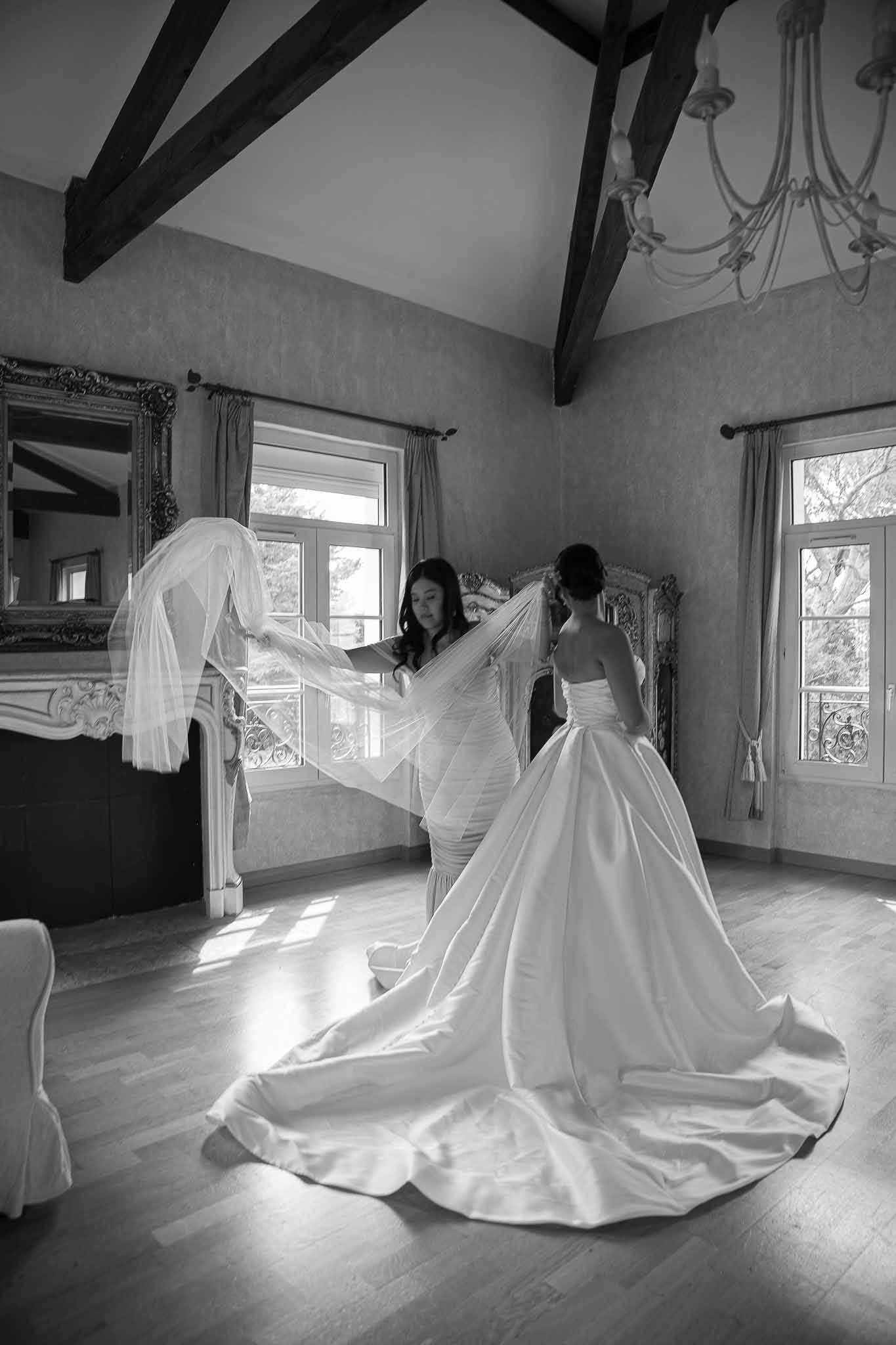 Bride having veil adjusted by attendants in historic bridal suite with exposed beams