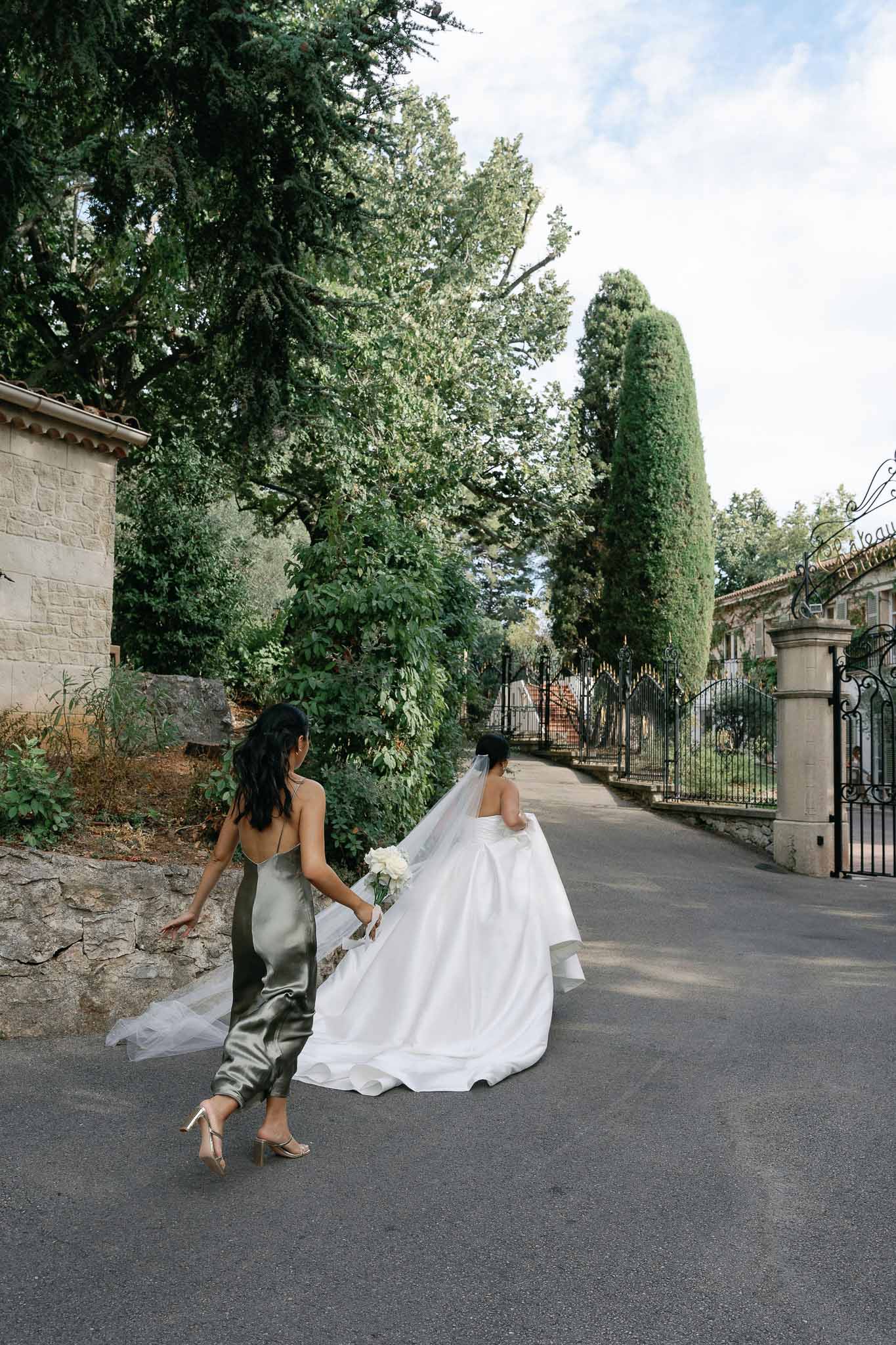 Bride and bridesmaid walking through stone courtyard at European garden estate