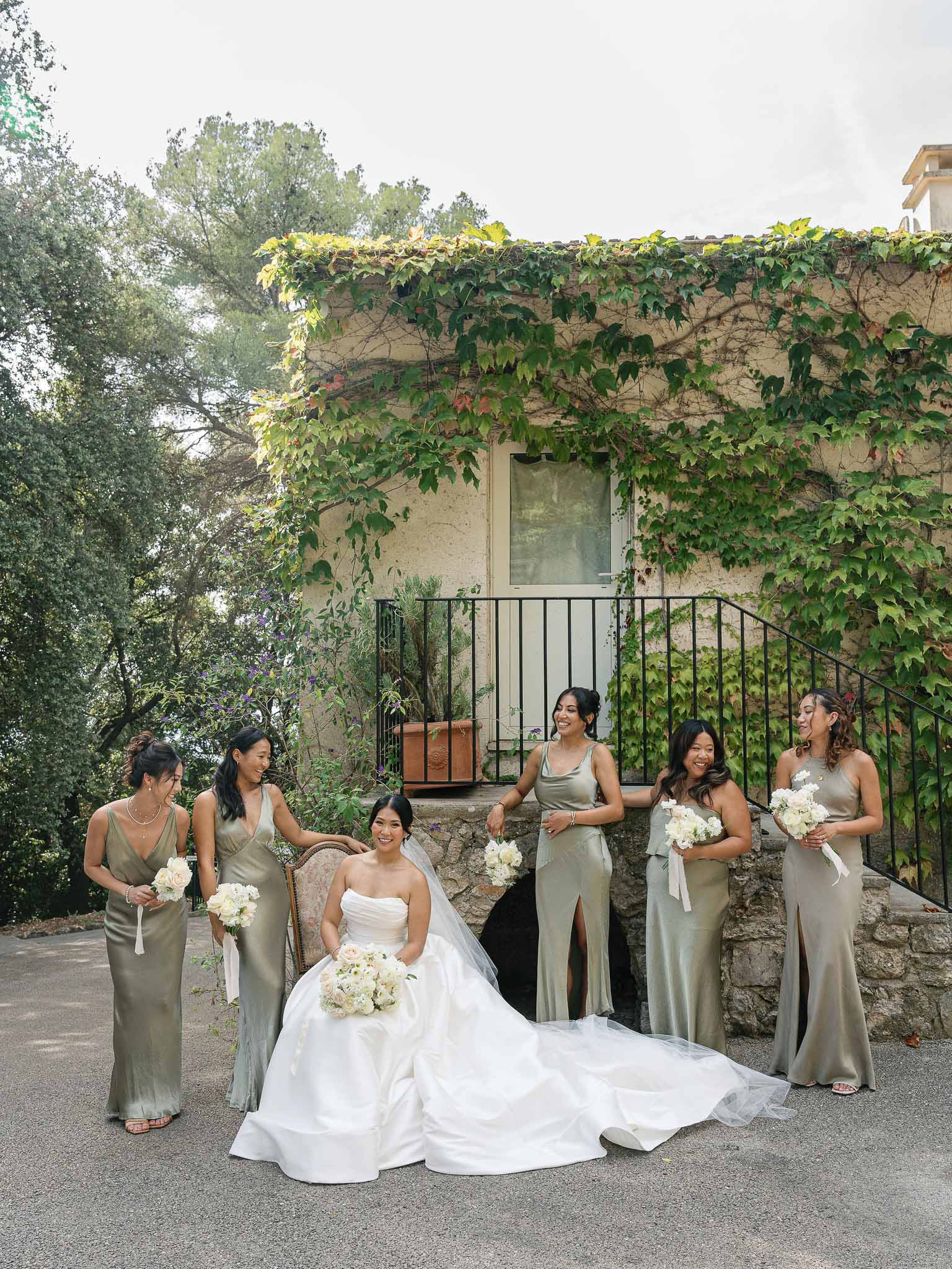 Bride and five bridesmaids posing in stone courtyard at classic ivy-covered venue