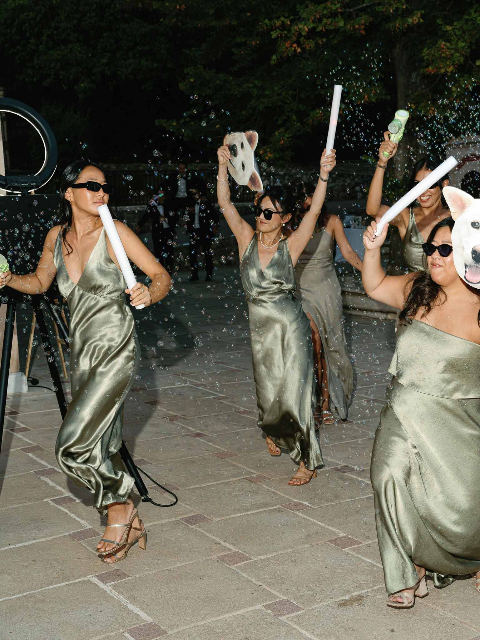 Bridal party celebrating with champagne and scrolls on outdoor terrace at night reception
