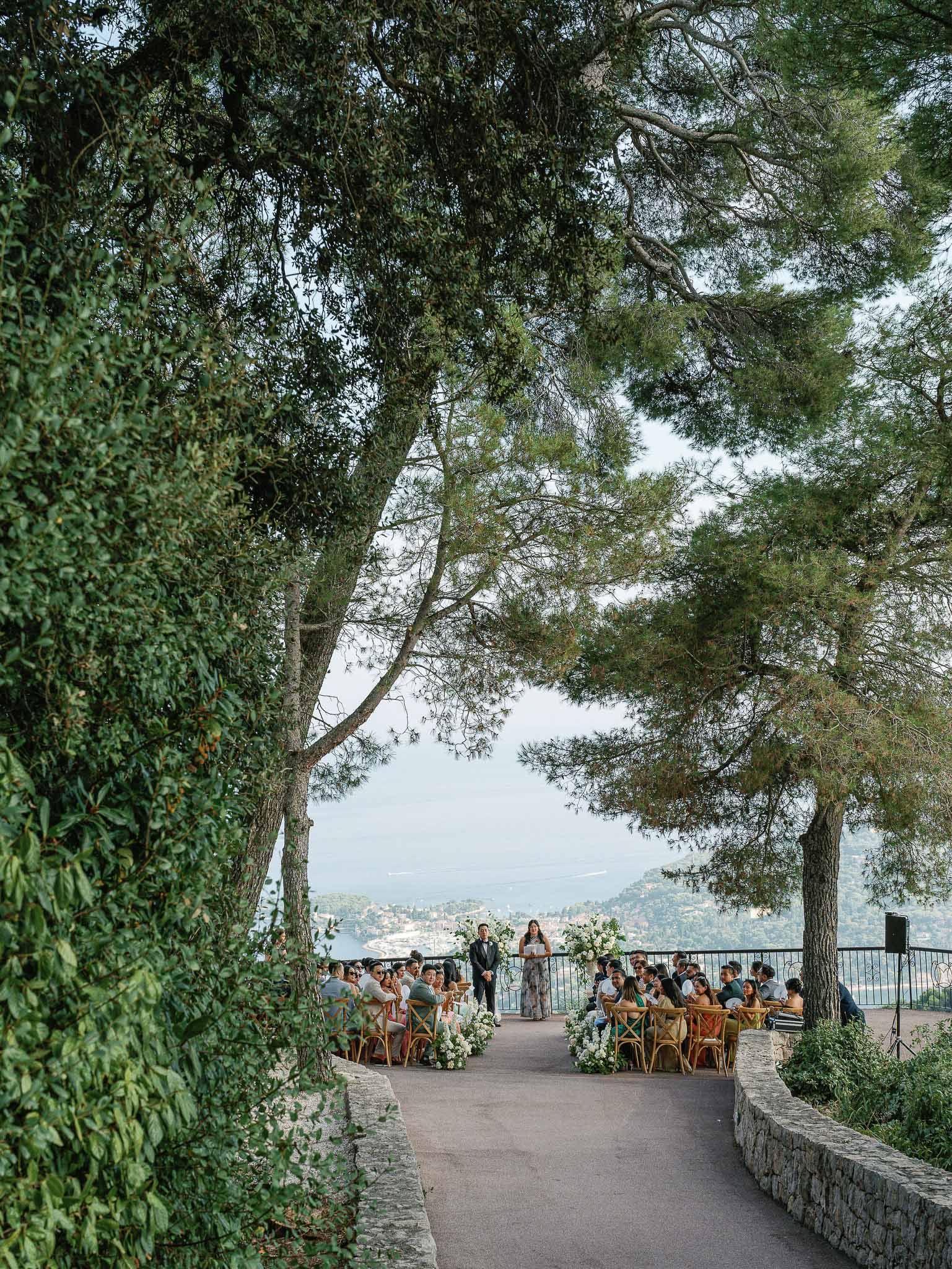 Outdoor wedding ceremony on terrace with mountain views and natural tree archway