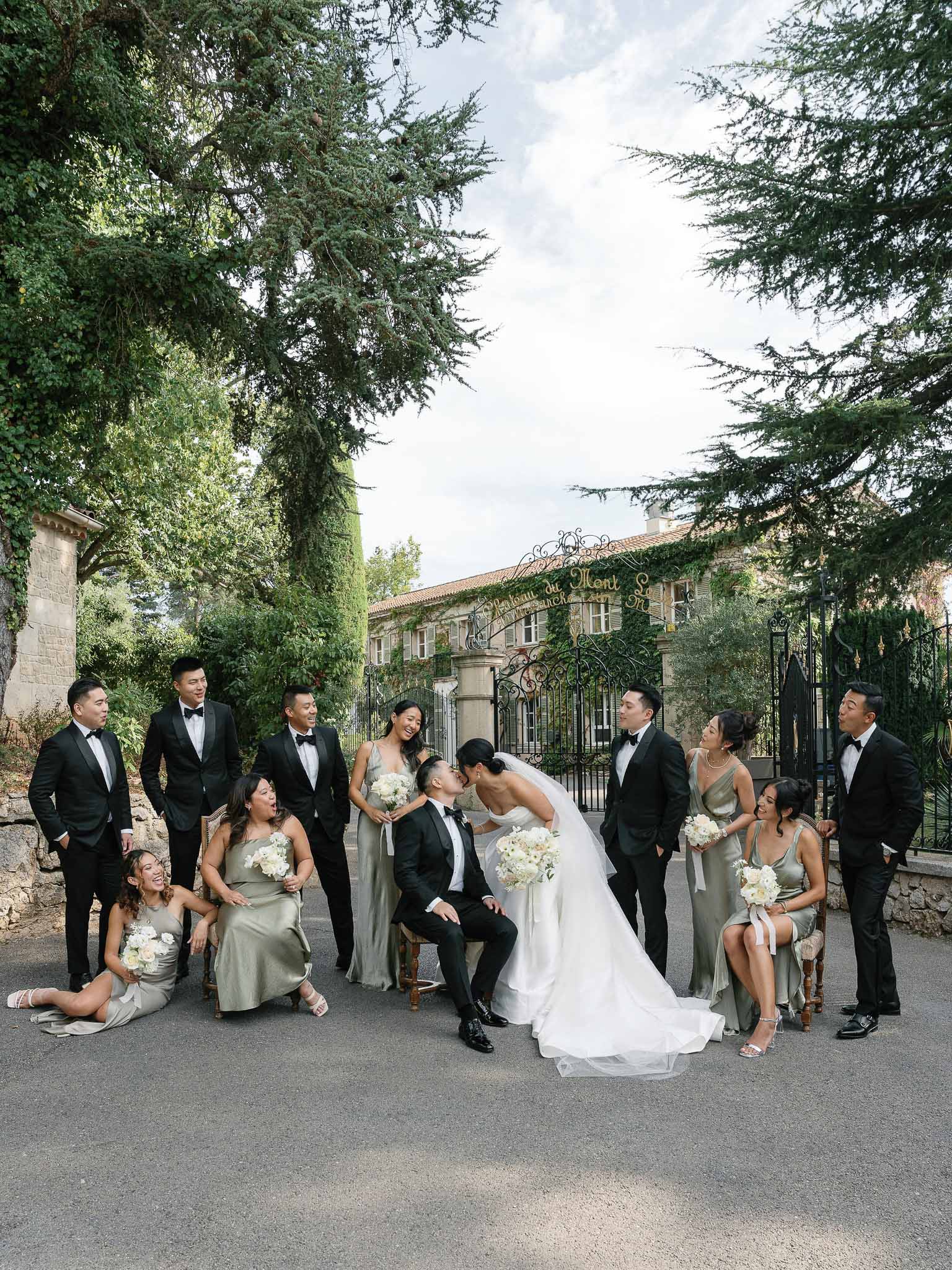Formal bridal party portrait with bride, groom and attendants in ivy-covered courtyard with stone architecture