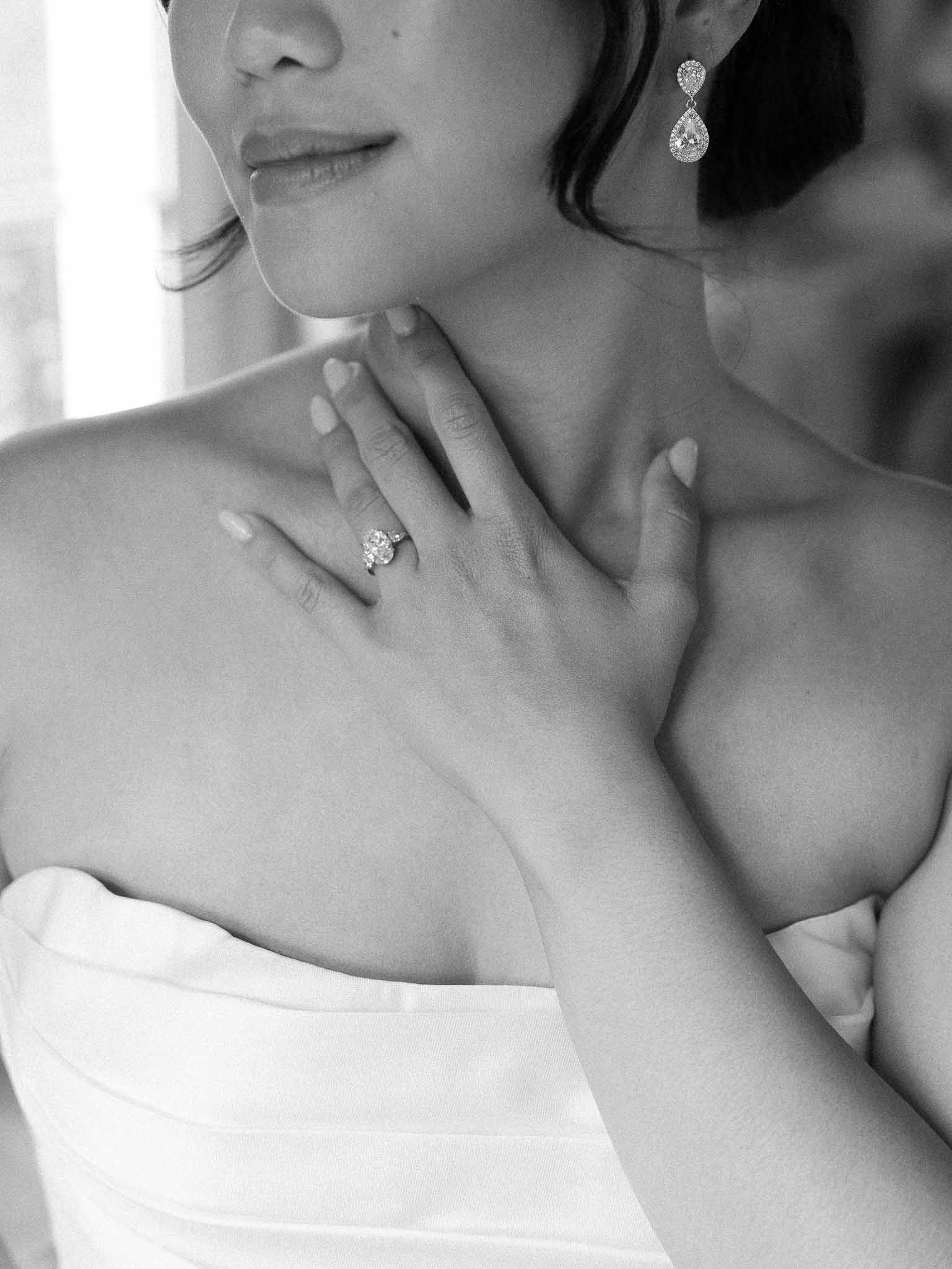 Black and white close-up bridal portrait showing jewelry and dress details
