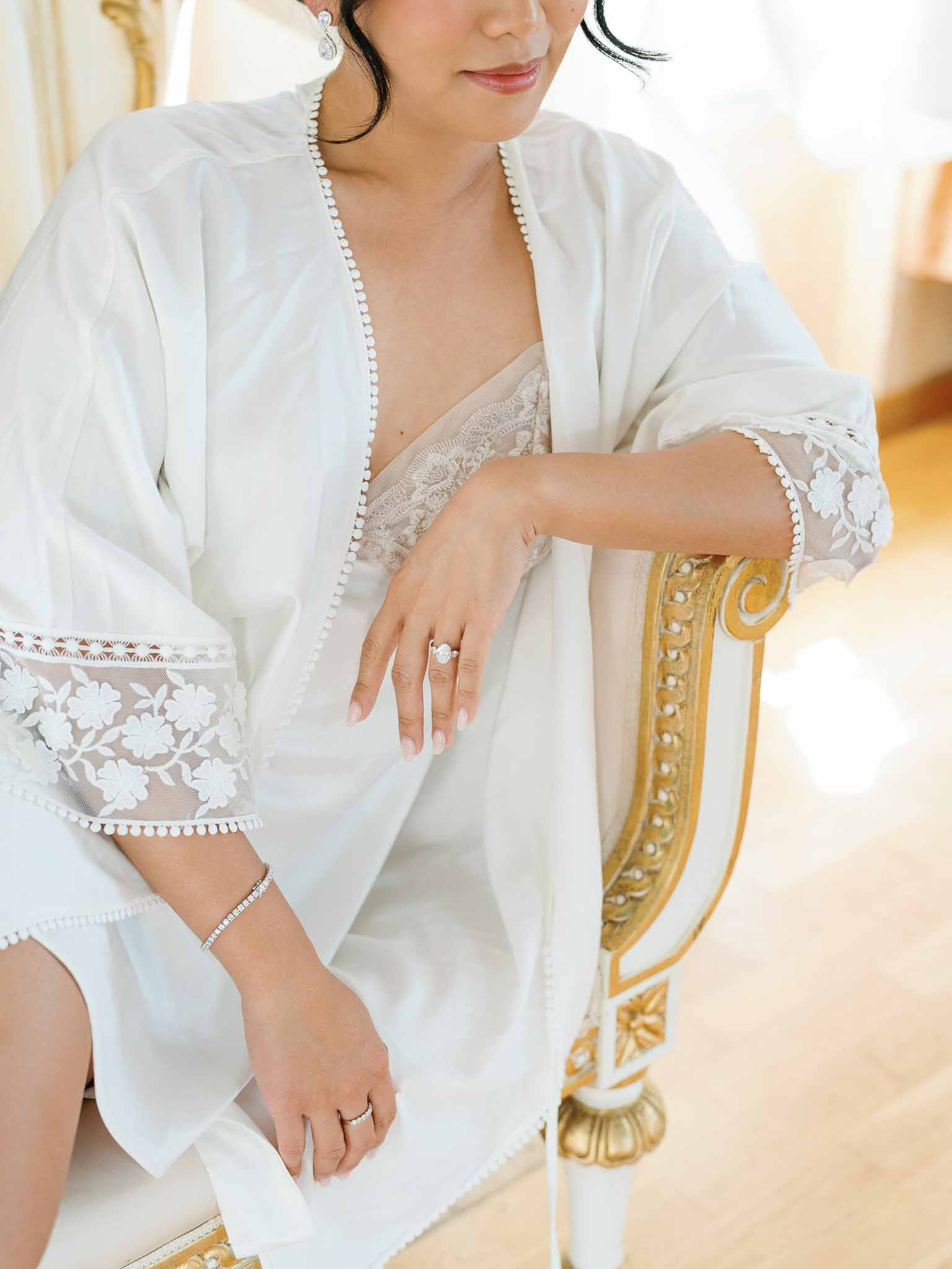 Bride in ivory silk robe with pearl jewelry during getting ready preparations