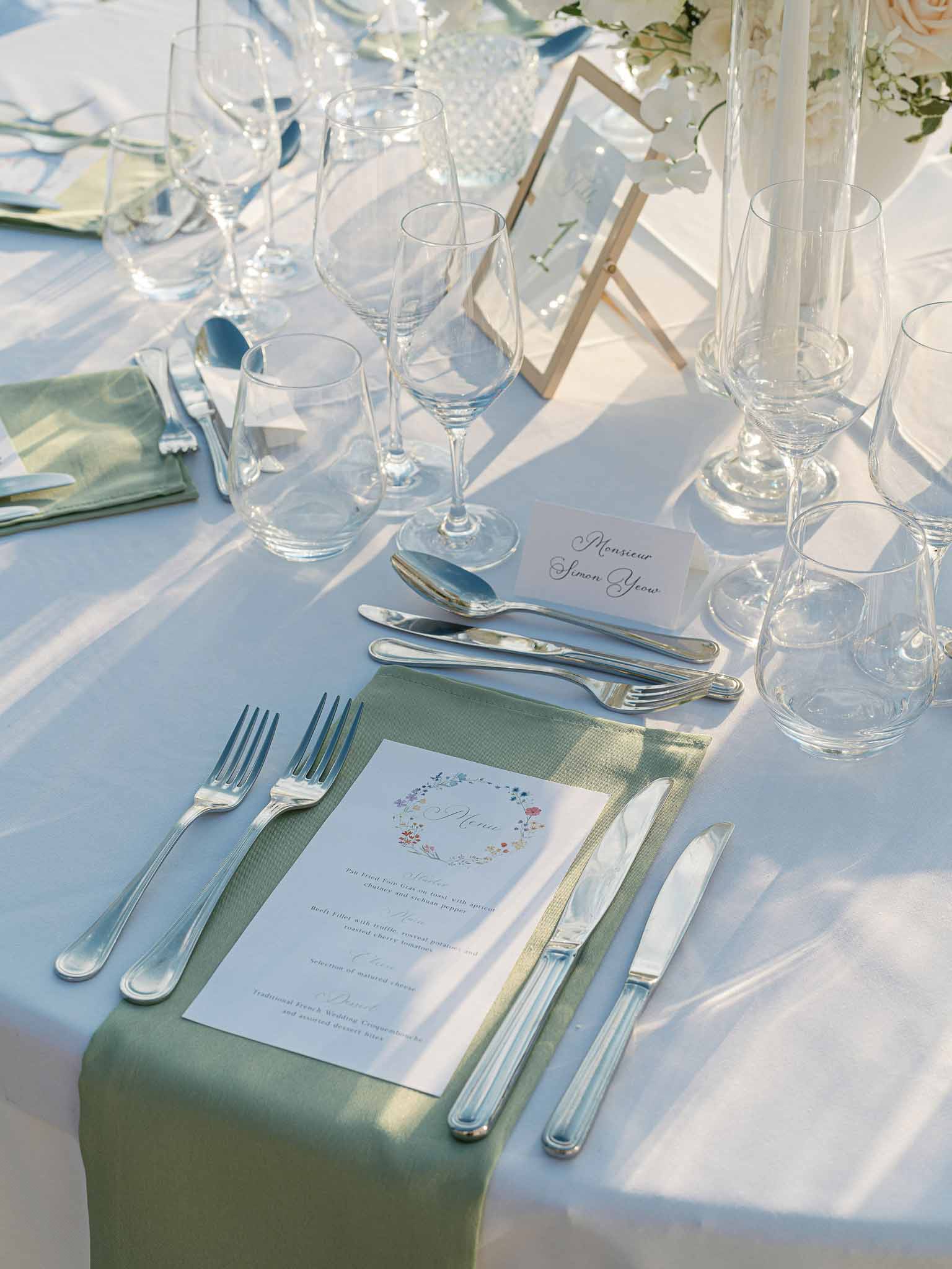 Formal reception table setting with place card and menu at outdoor wedding venue