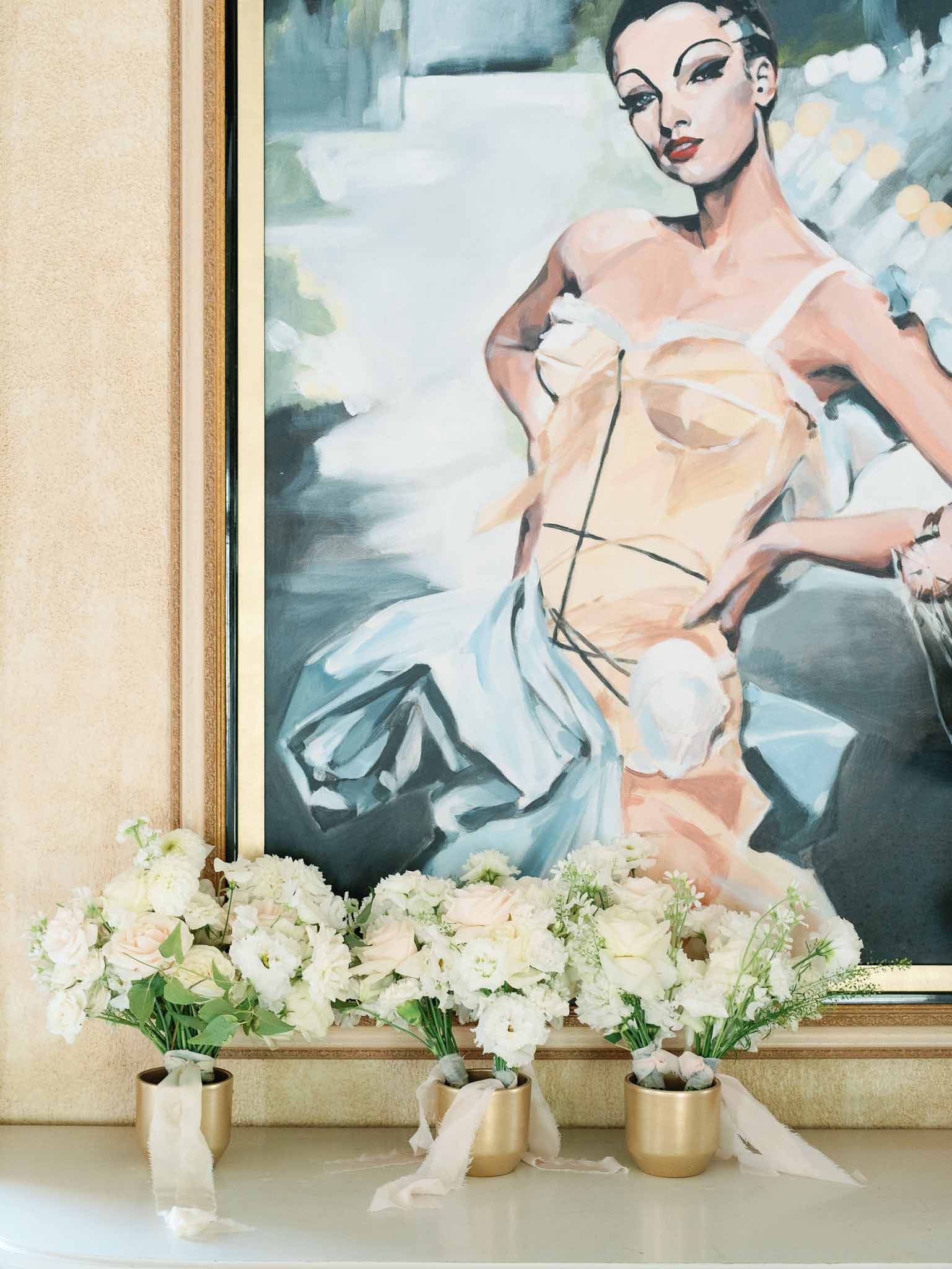 White floral arrangements in gold vessels displayed as bridal room decor styling