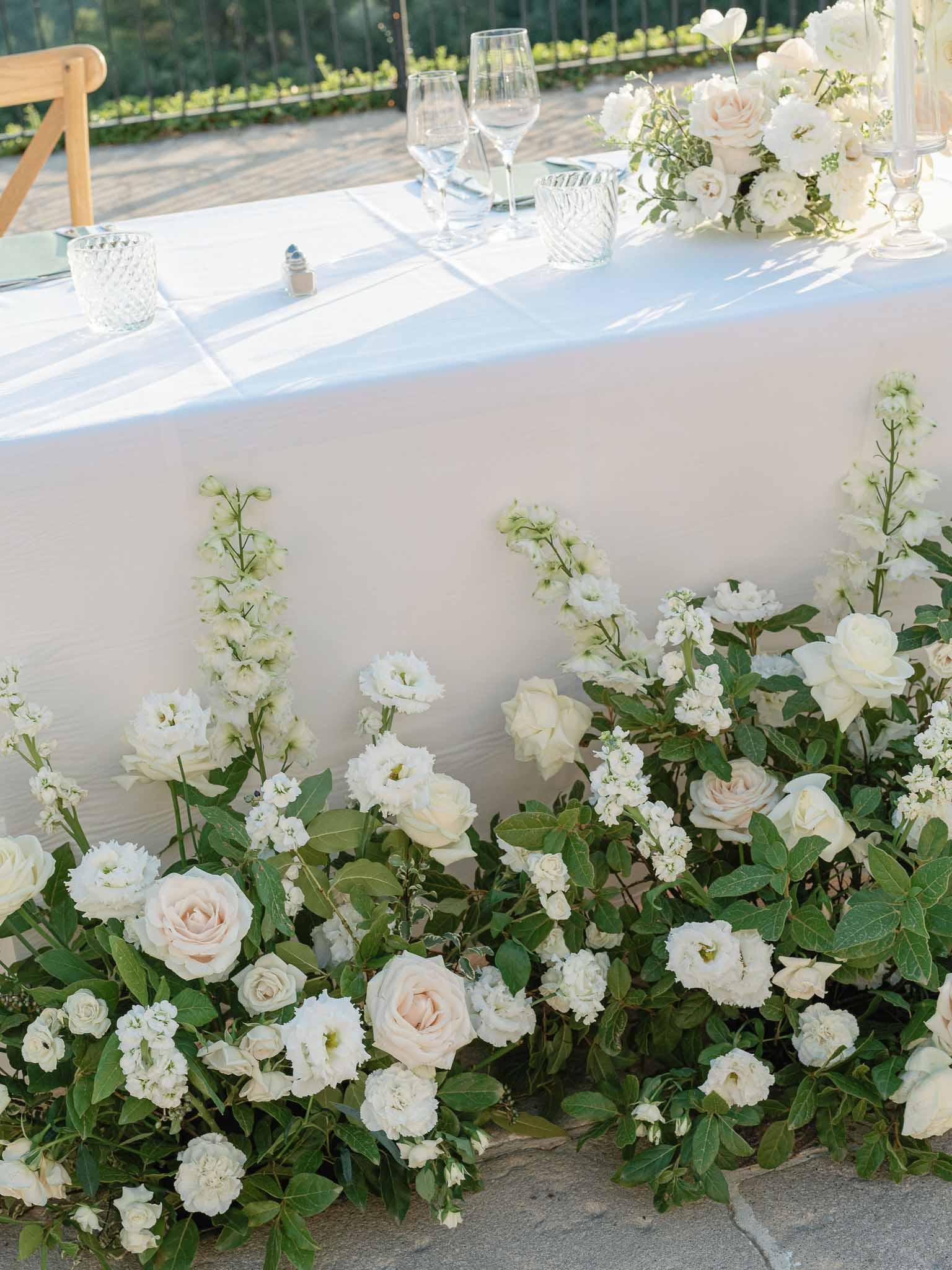 Wedding reception table setting with white floral garland at outdoor garden venue