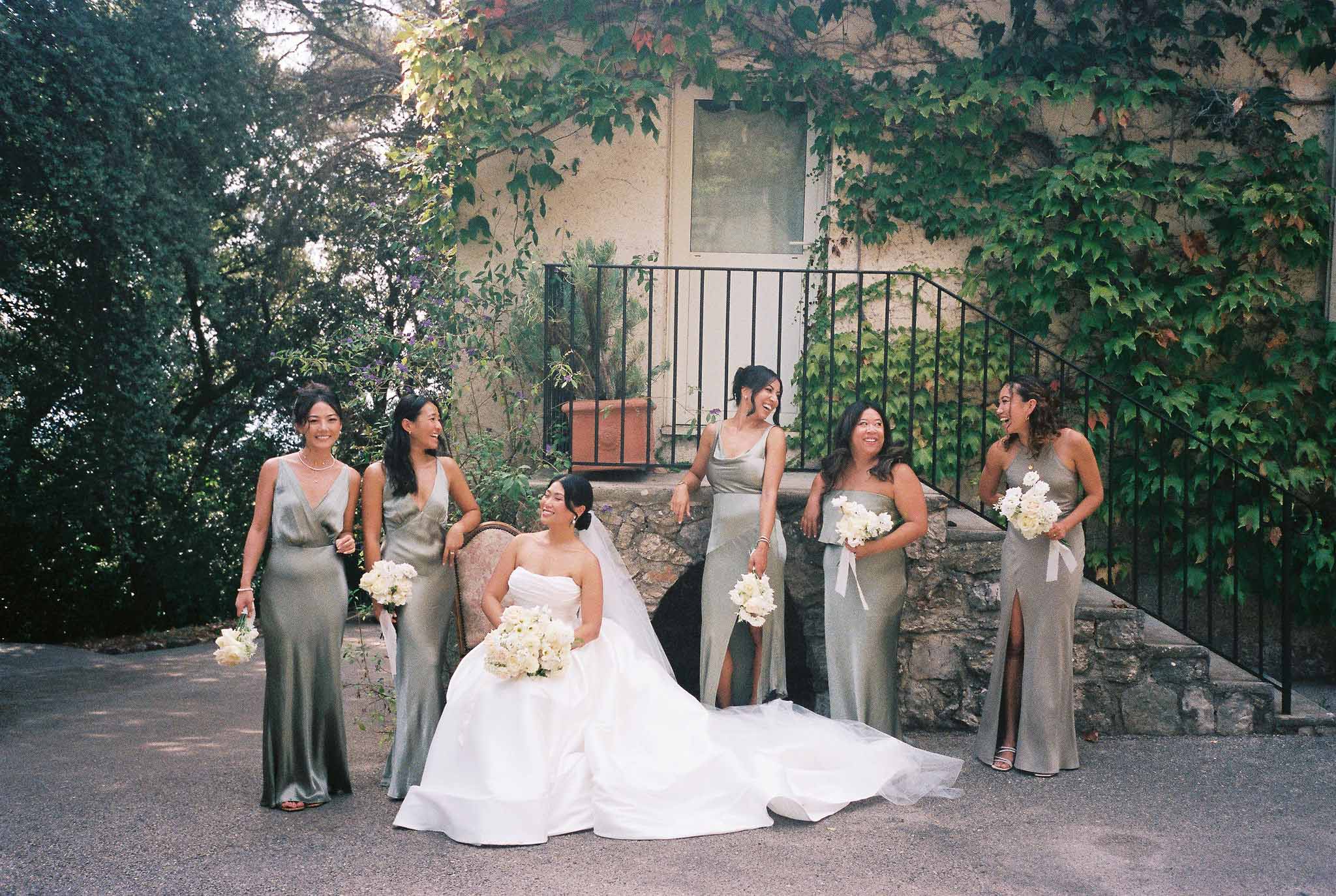 Bride and bridesmaids formal group portrait at ivy-covered stone building courtyard
