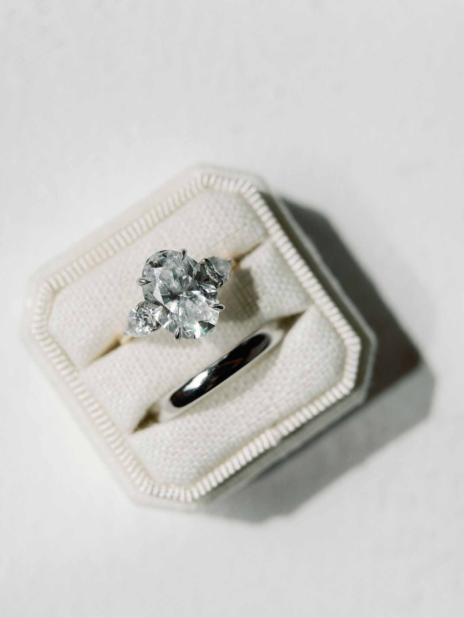 Wedding rings in cream ring box with diamond engagement ring and black wedding band